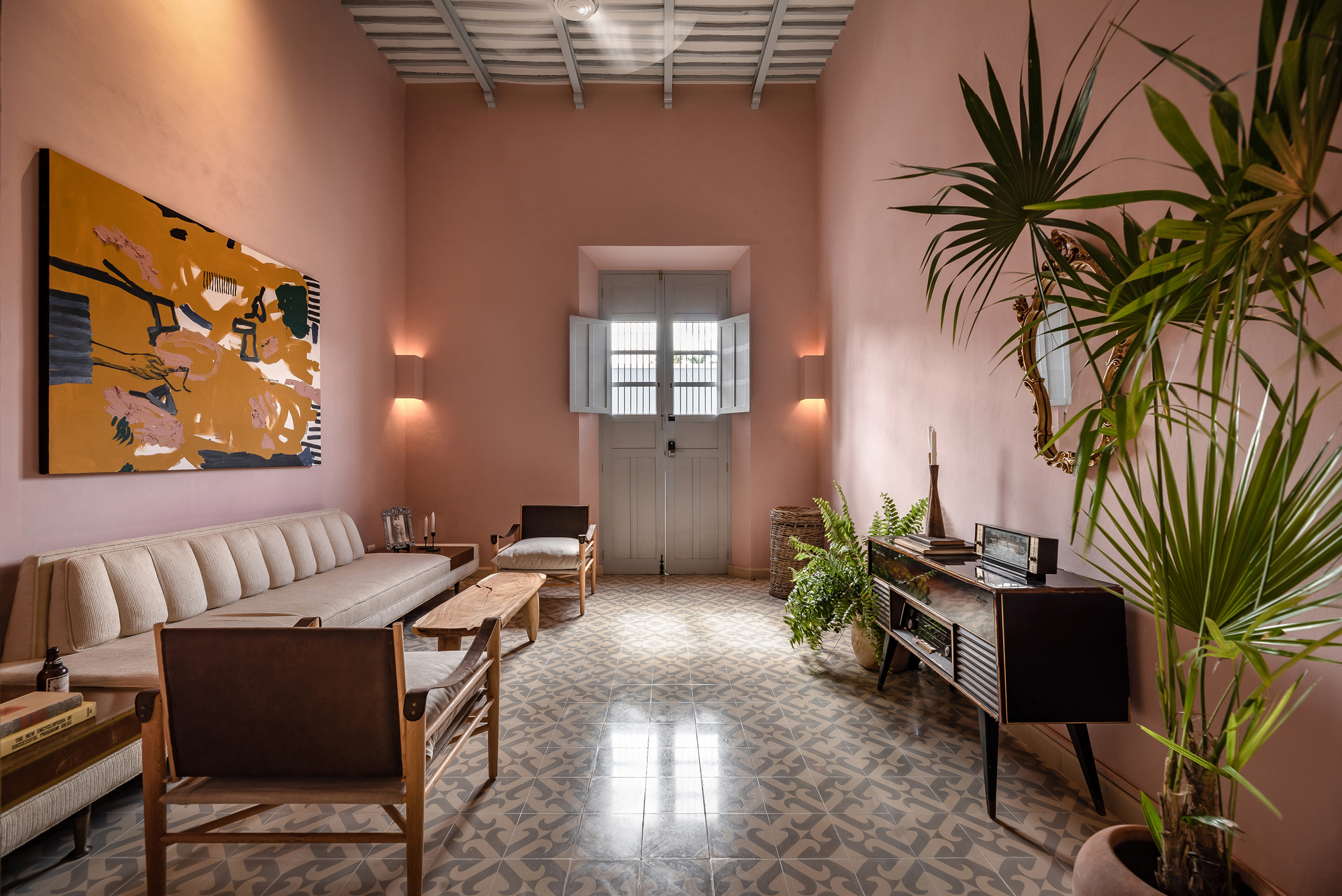 Living room with patterned tile floor and pink walls beneath an exposed timber rafter ceiling