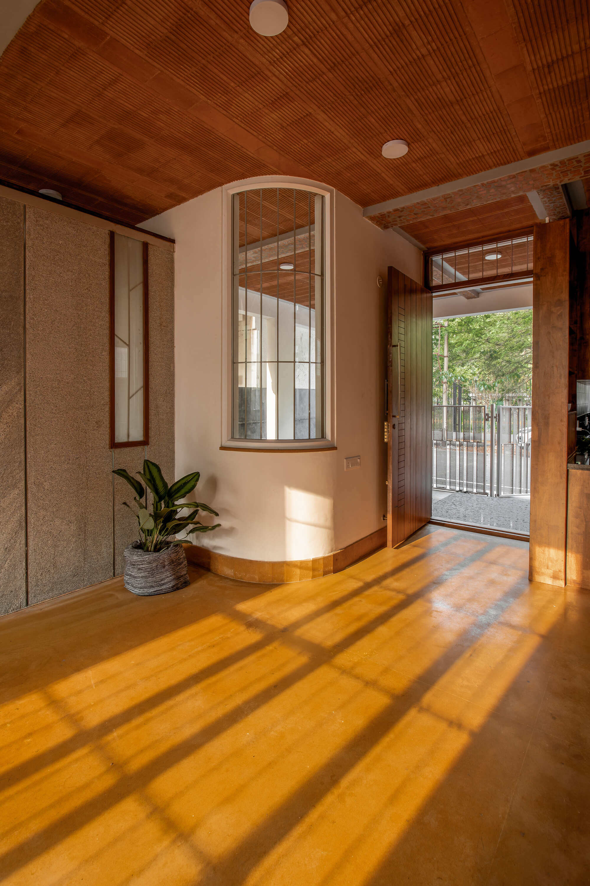 Arched window alcove with amber concrete floor casting long shadow bars from the gridded glazing in morning light
