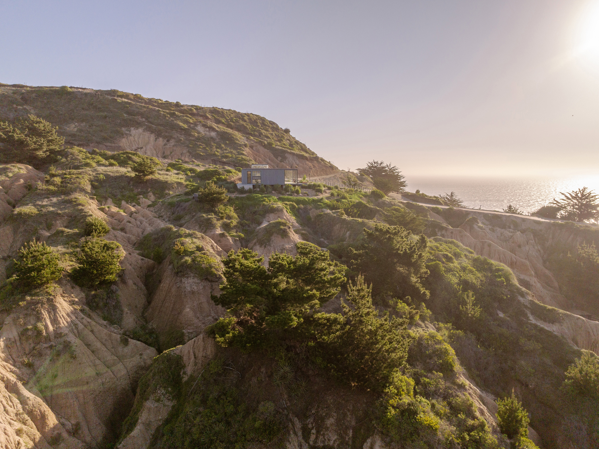 Distant view of the structure perched on a coastal hillside covered in green vegetation at golden hour