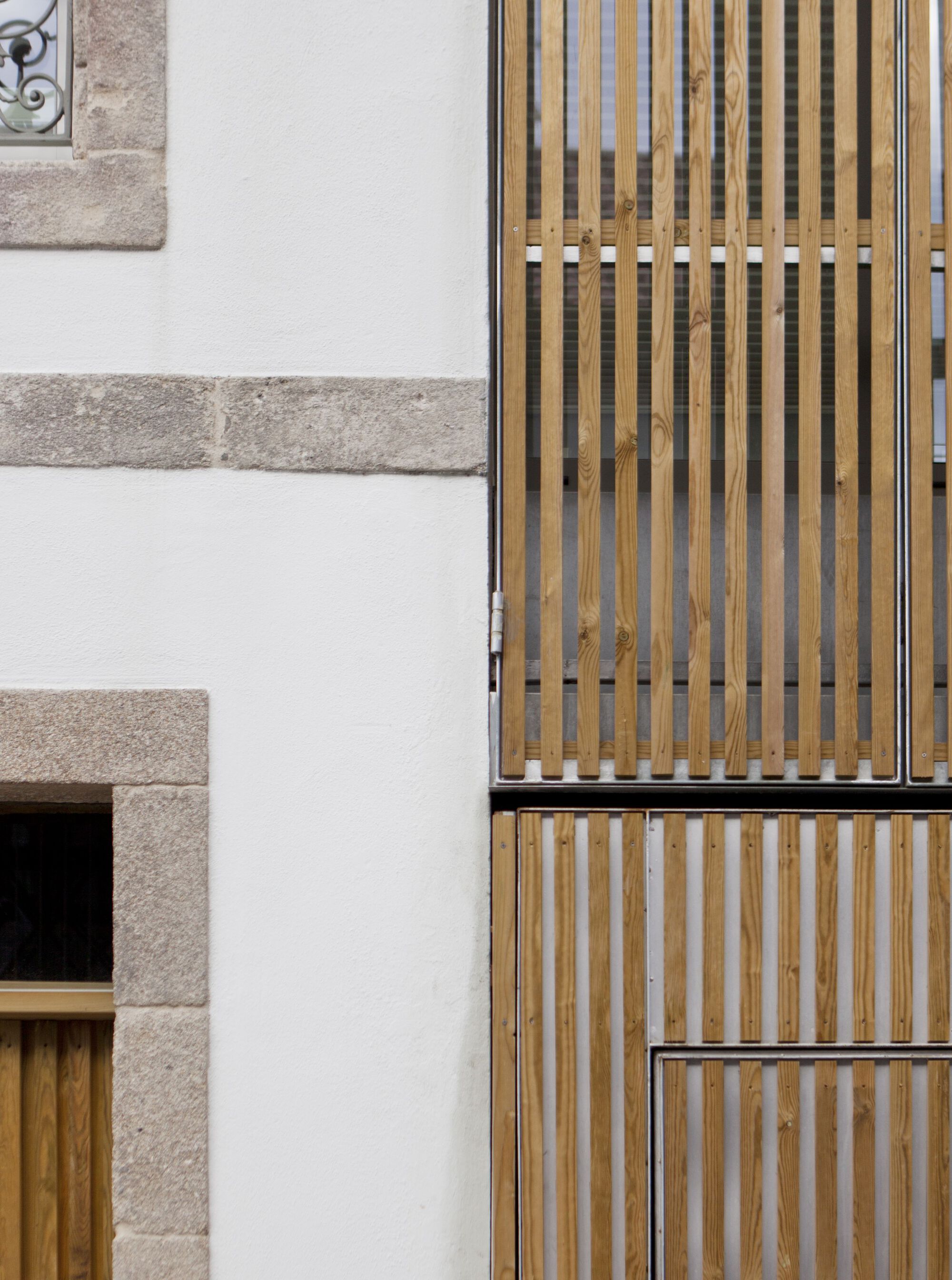 Detail of vertical timber slat screens against white stucco wall with granite quoins at window opening