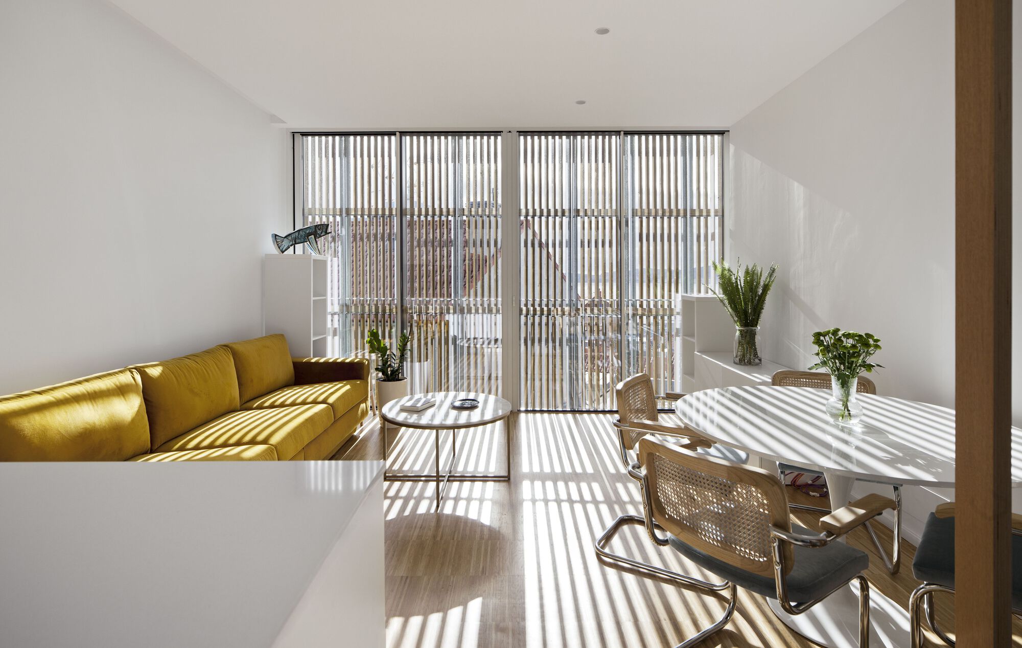 Living room with vertical timber screen casting striped shadows across the floor and furniture