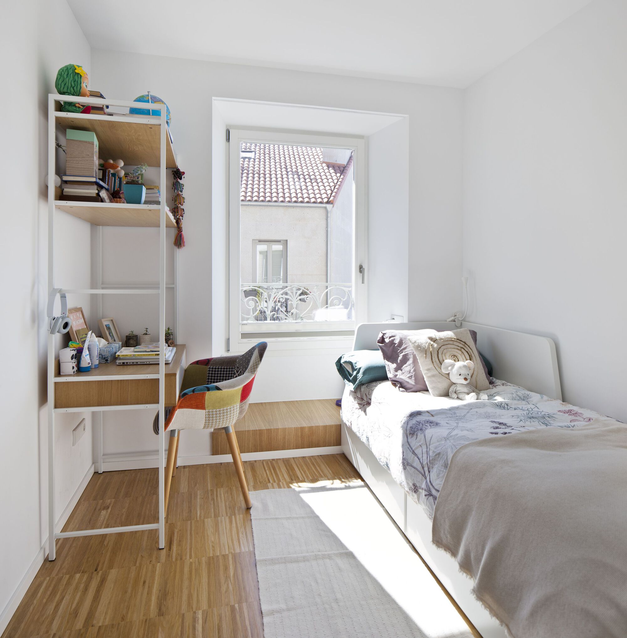 Bedroom with built-in shelving and a window framing a view of clay tile roofs