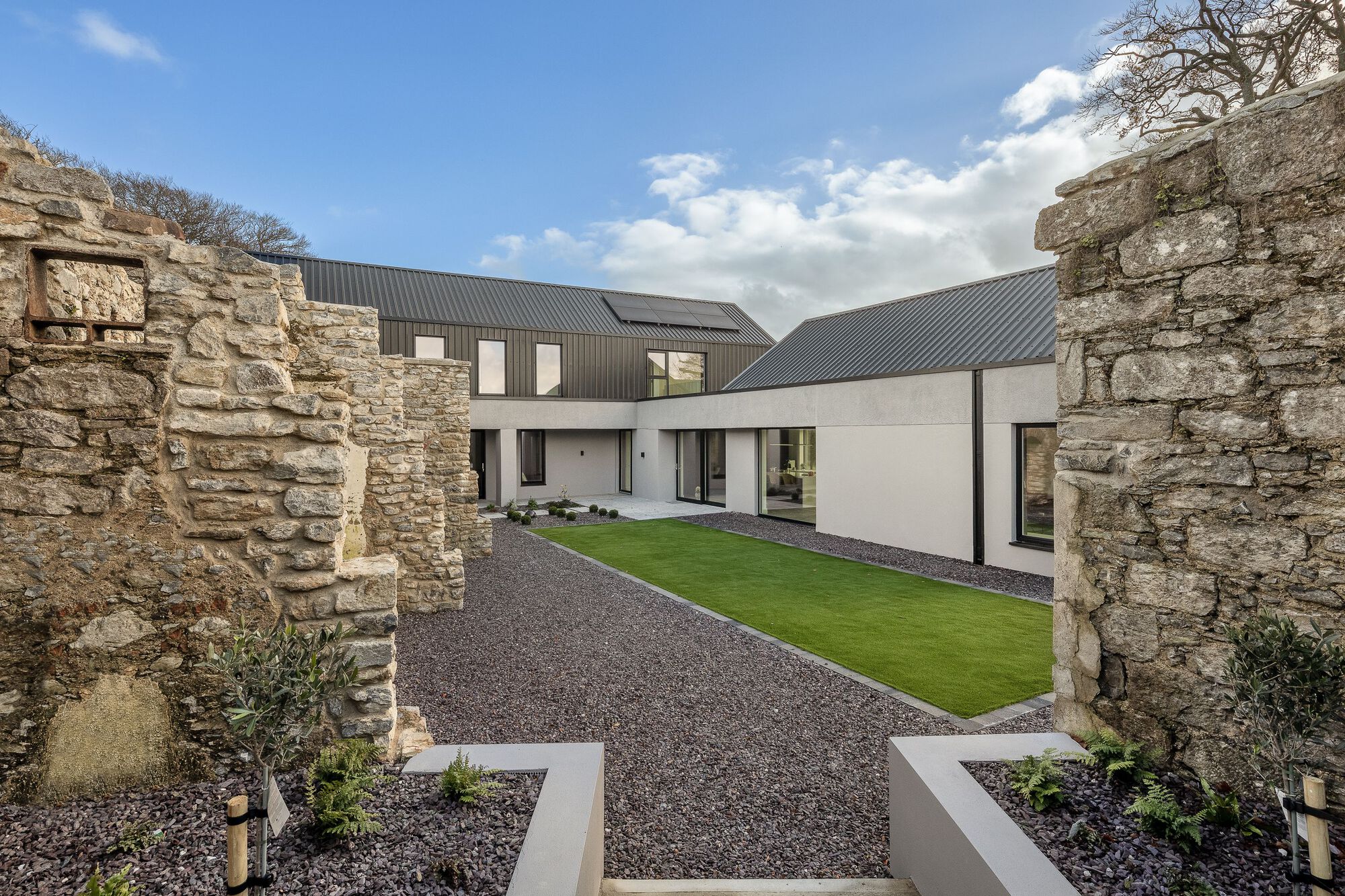 Courtyard framed by preserved stone ruin walls with gravel ground and planted beds