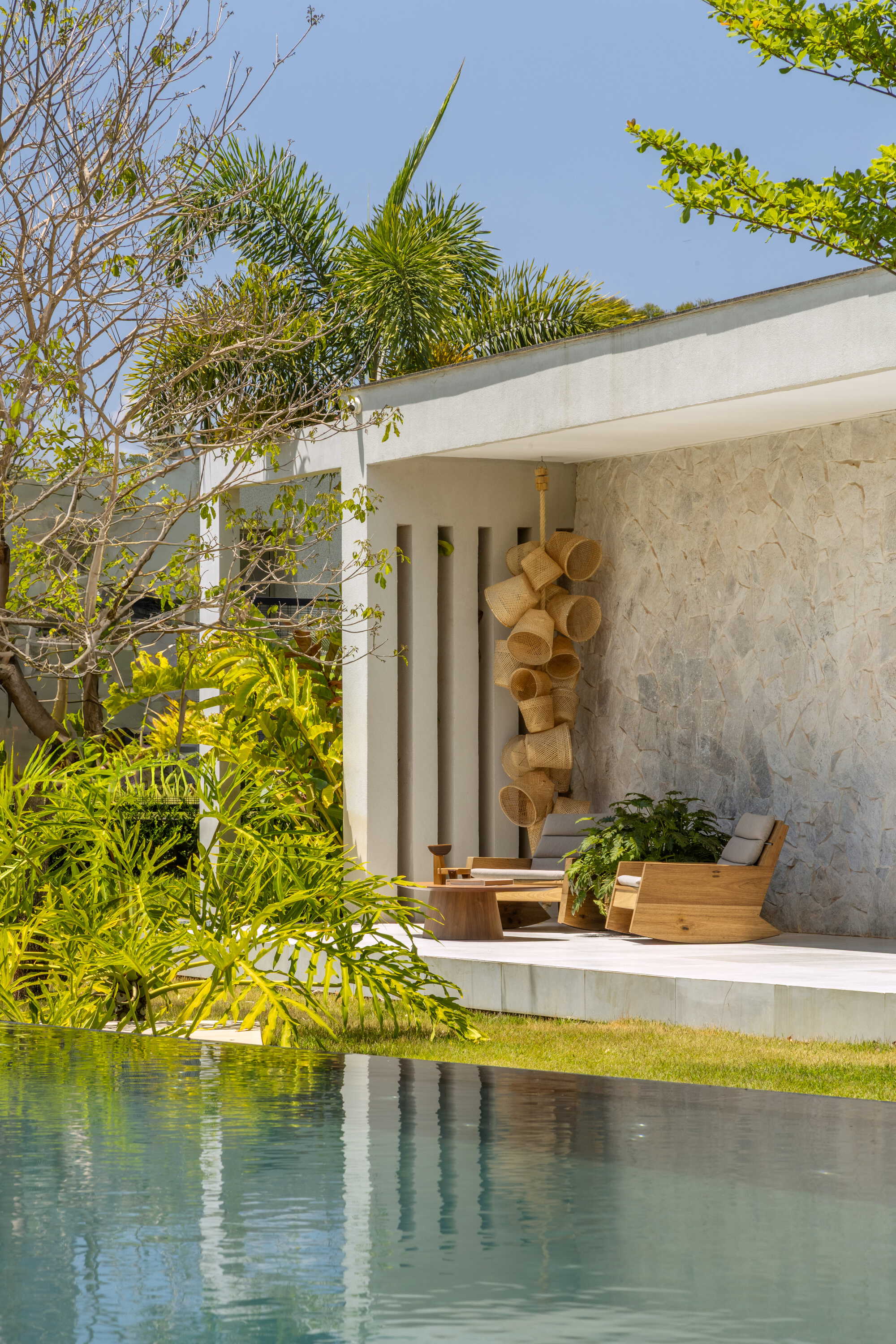 Pool edge with outdoor seating platform framed by vertical screens and tropical landscaping