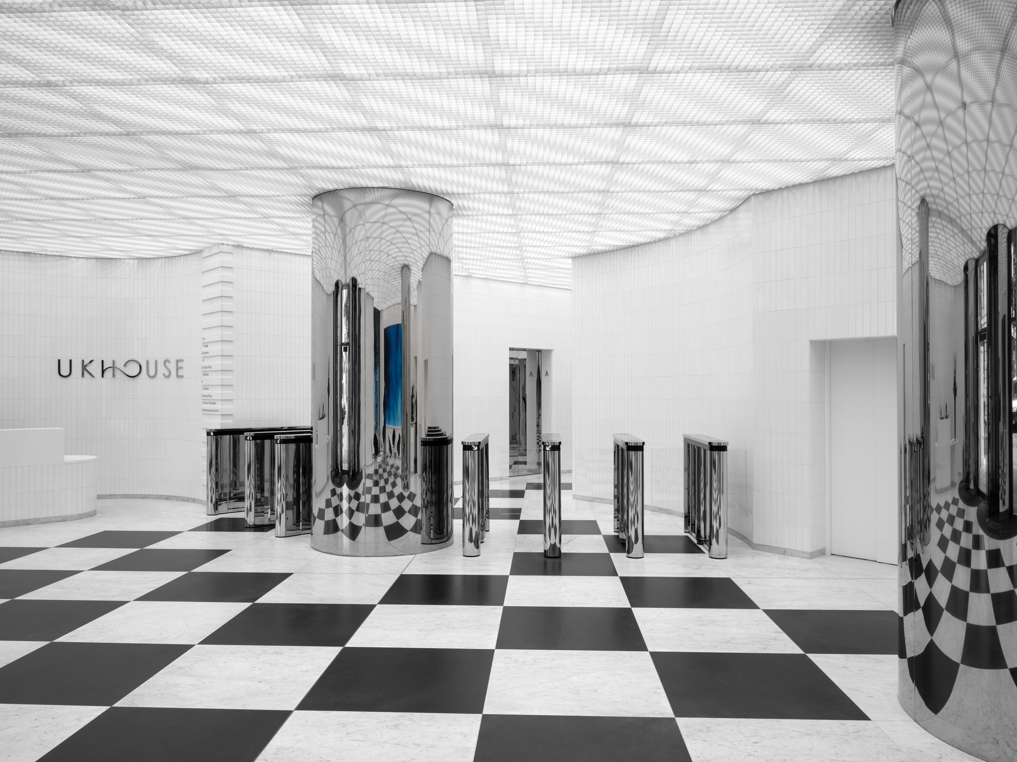 Interior lobby with polished chrome cylindrical turnstiles on a black and white chequered floor