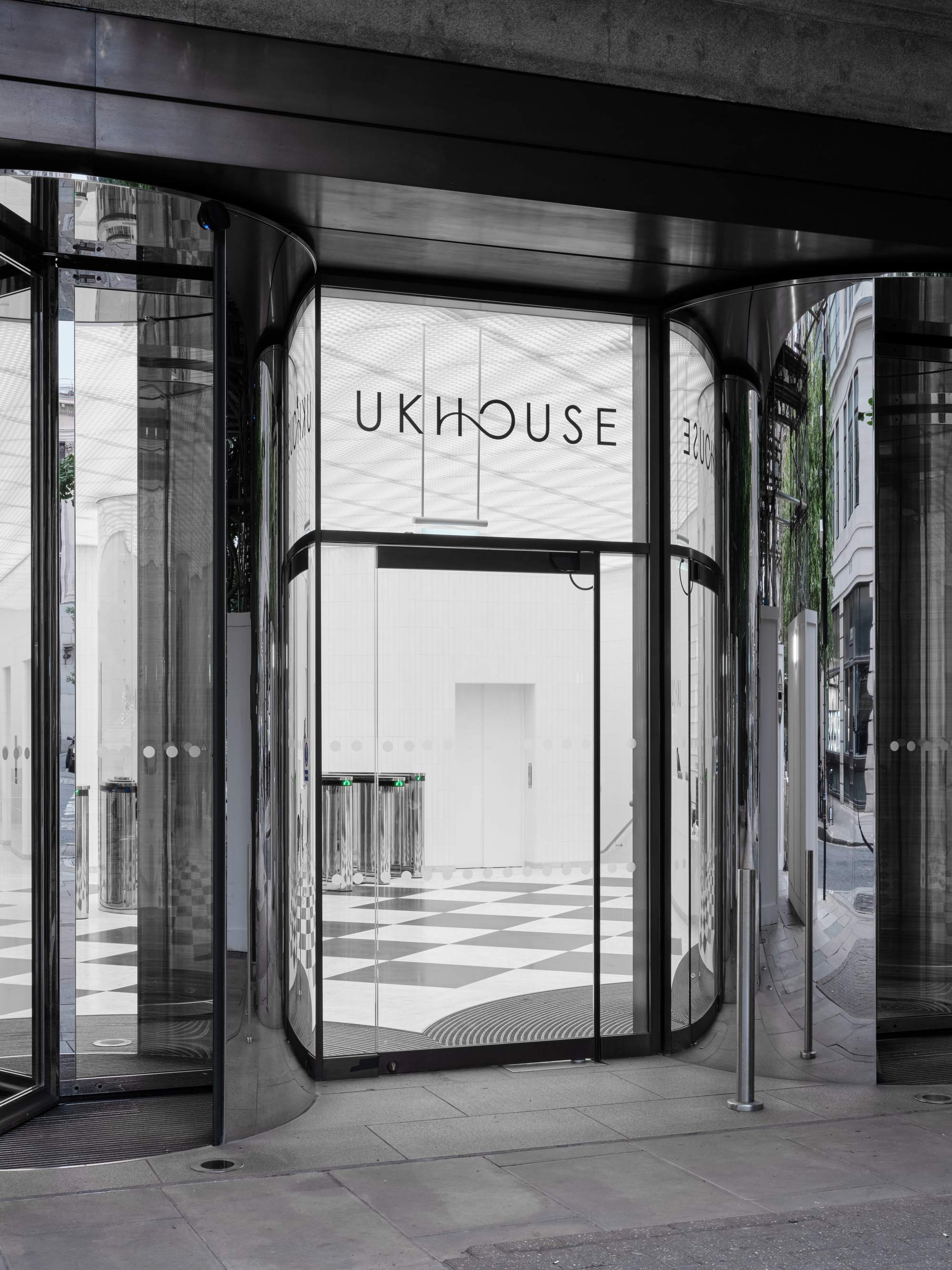 Close-up of the revolving door vestibule with curved chrome panels and view into the chequered lobby