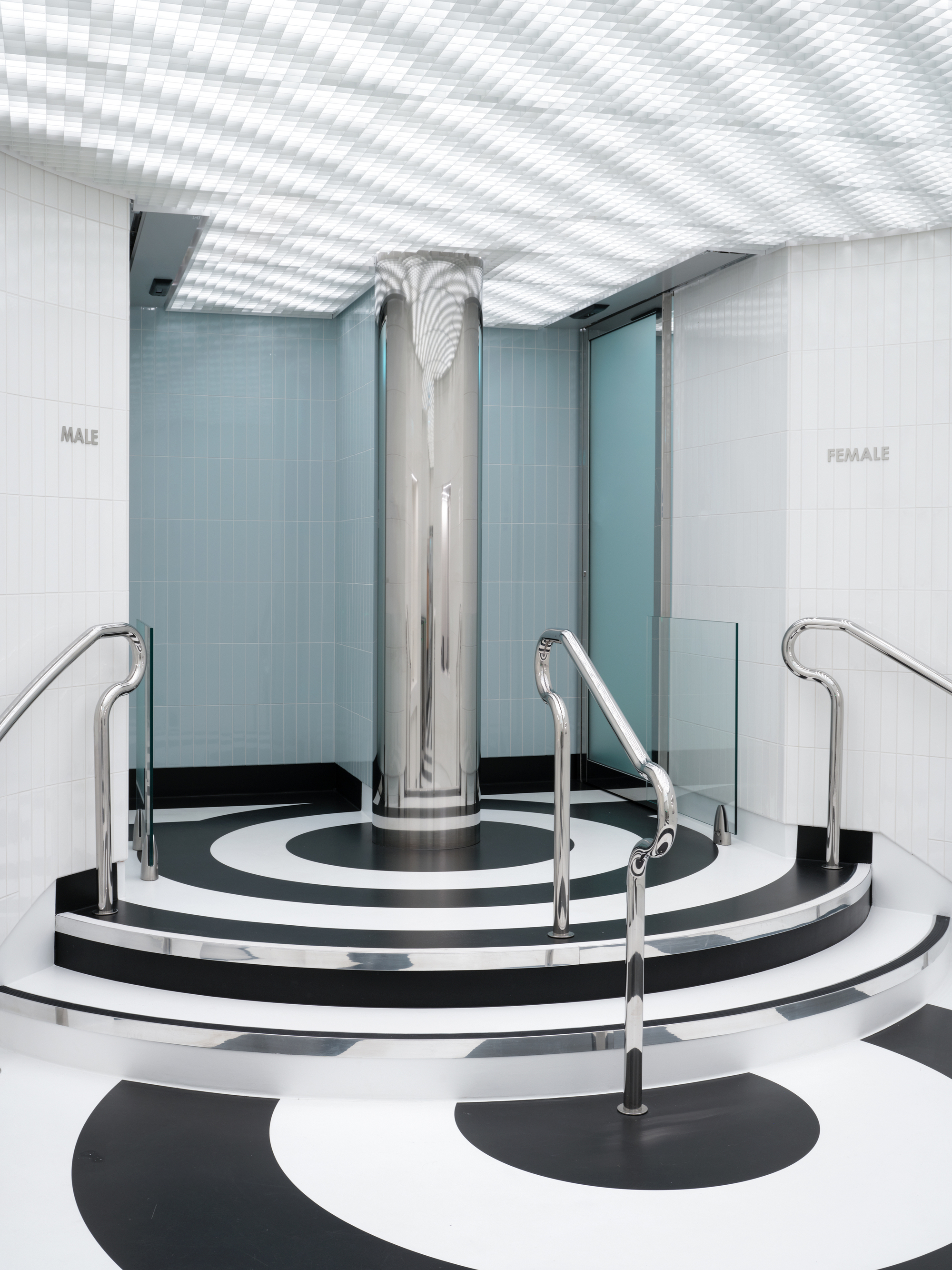 Circular platform with chrome column and handrails on concentric black and white striped flooring