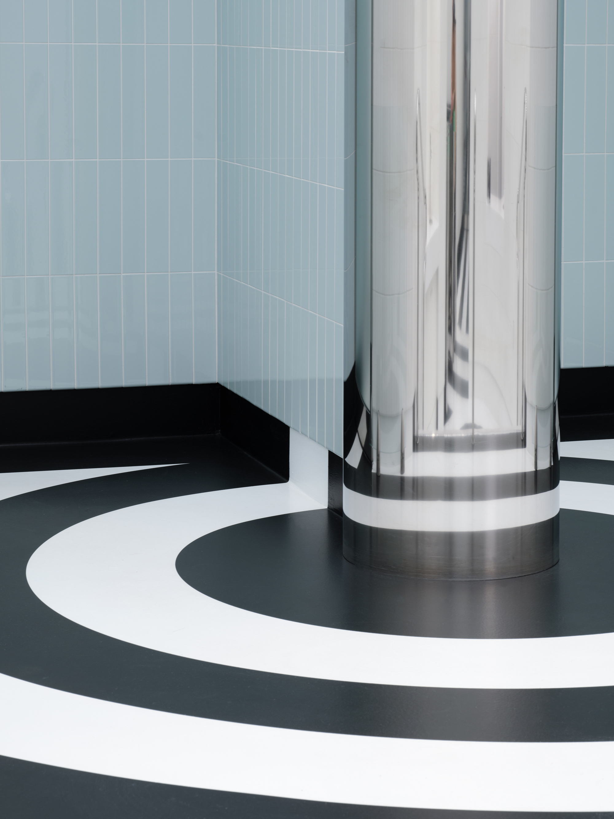 Polished metal column base meeting concentric black and white circular floor pattern