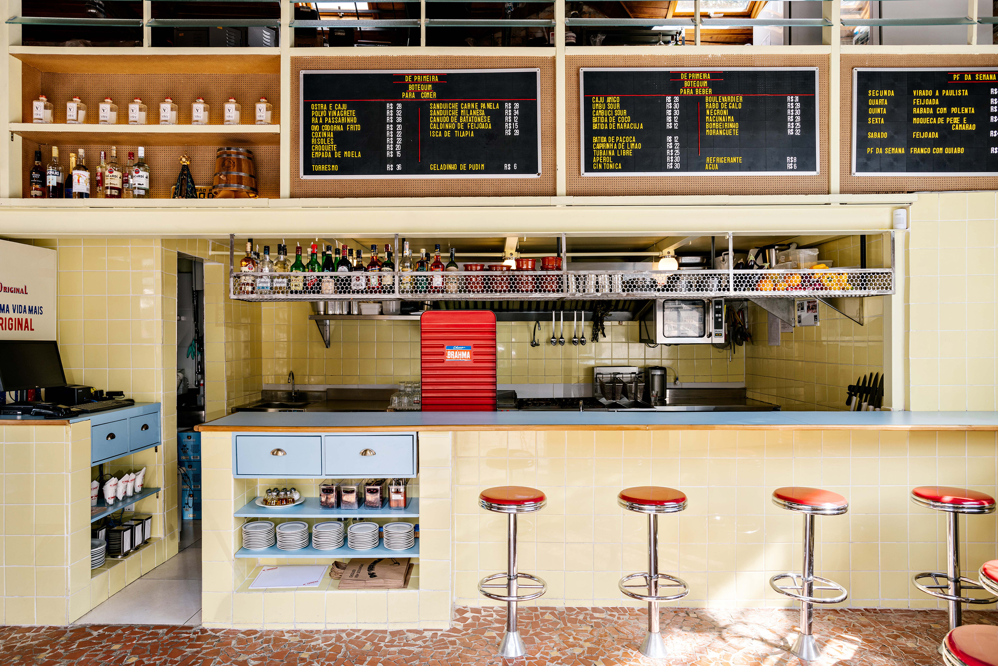 Service counter with yellow tile backsplash, red rolling shutter, chrome bar stools and digital menu boards above