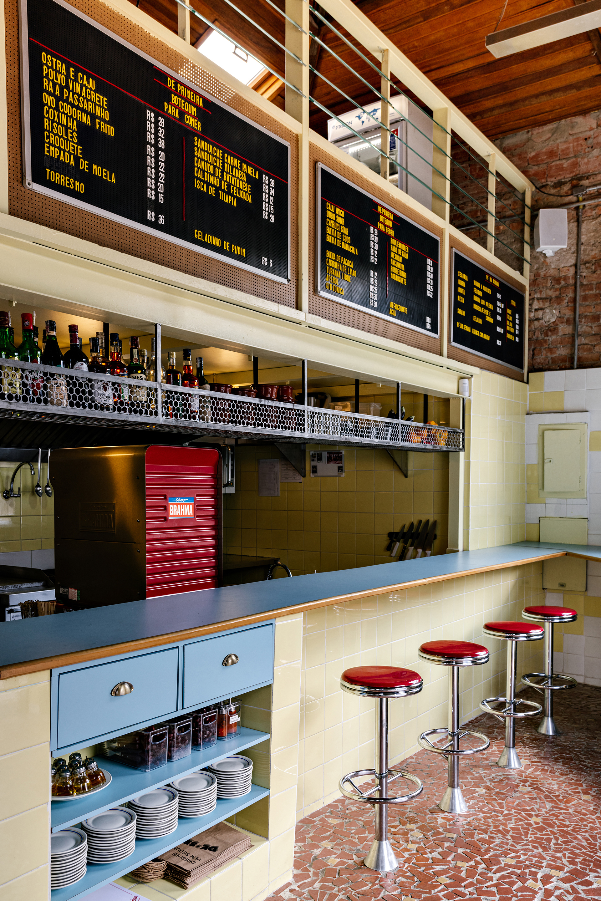 View of the bar counter showing exposed timber ceiling, digital menu screens and shelving with bottles