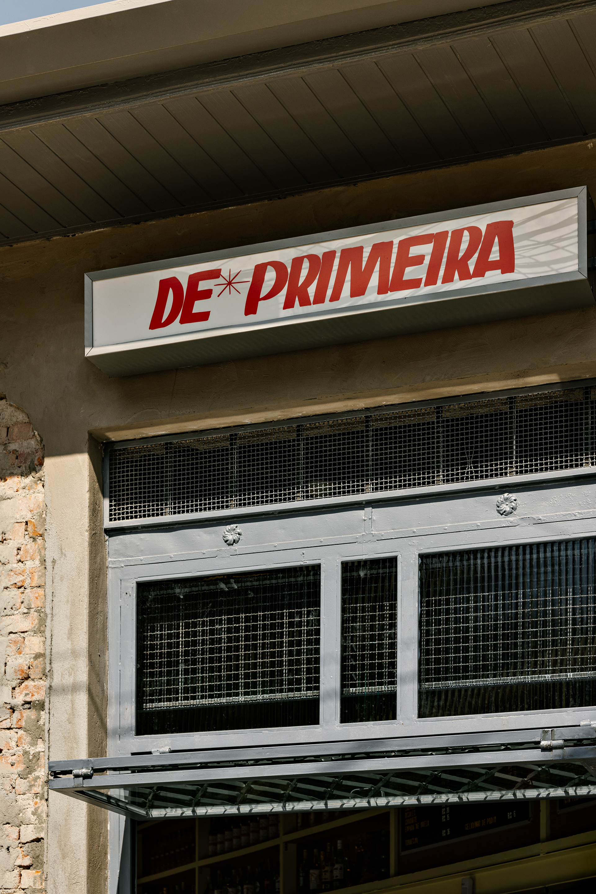 Close-up of signage and metal mesh ventilation panel under timber soffit at the entrance