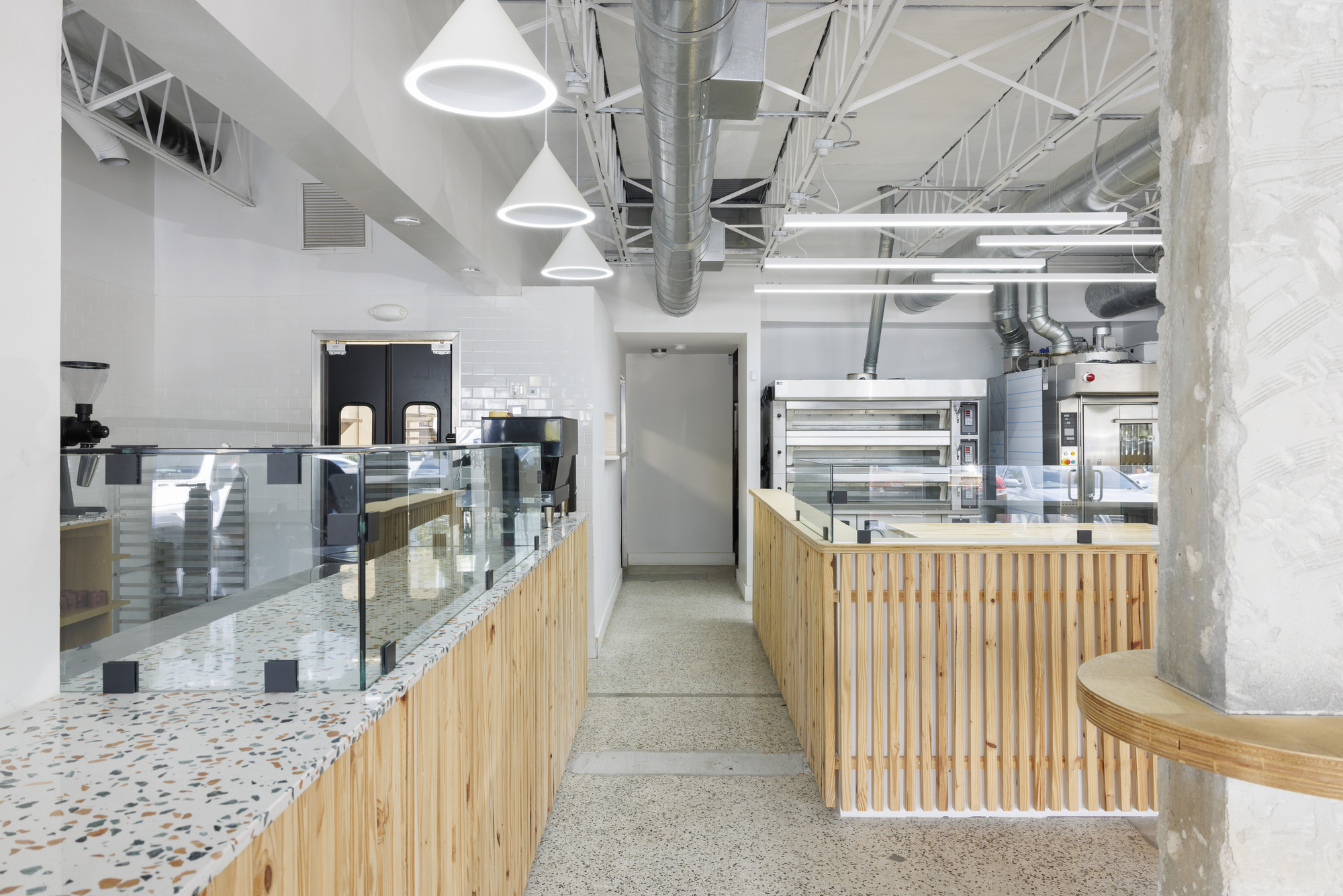 Service corridor between timber slat counters with terrazzo flooring and pendant lighting overhead