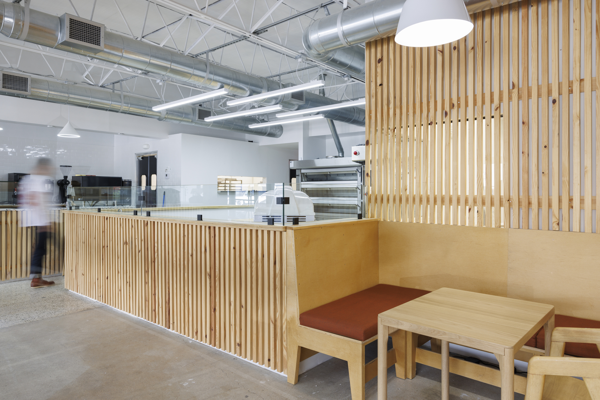 Interior view of the slatted timber counter and seating area with exposed ceiling trusses and ducting