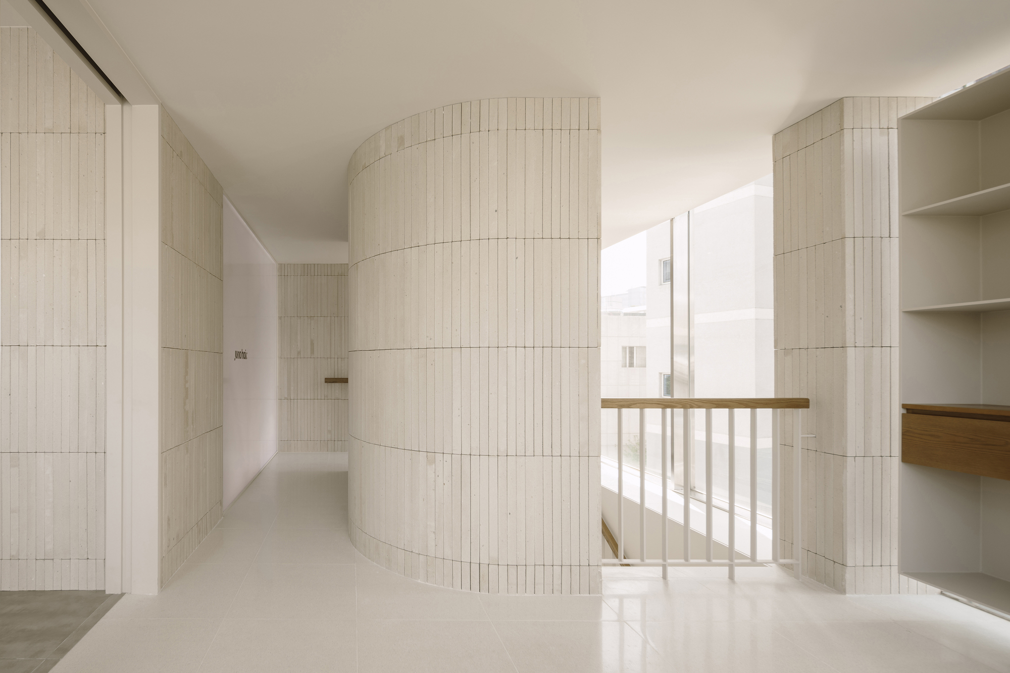 Curved ribbed tile volume around window opening with timber railing and daylight streaming in