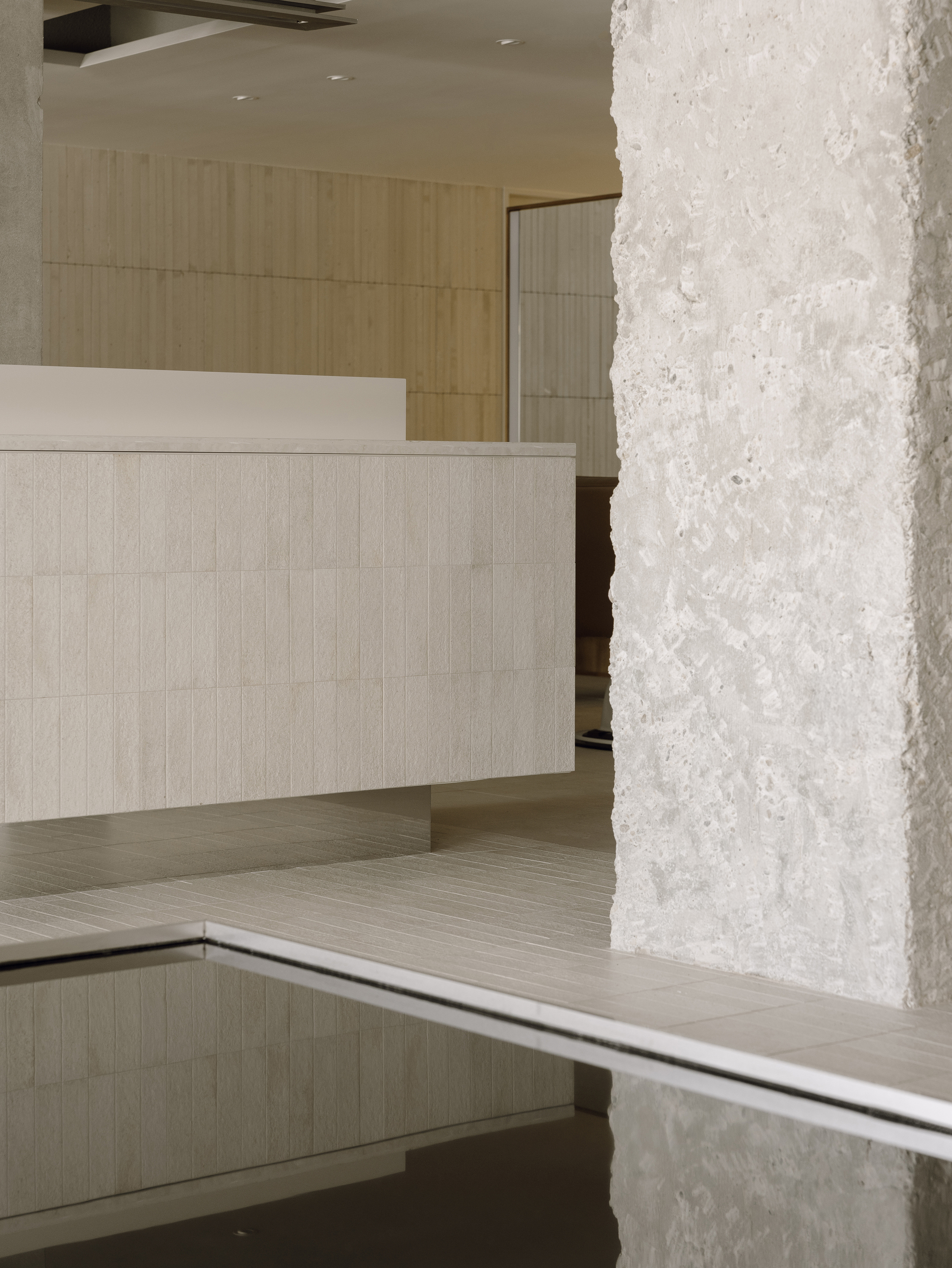 Close-up of textured white concrete column beside a pale tiled reception desk