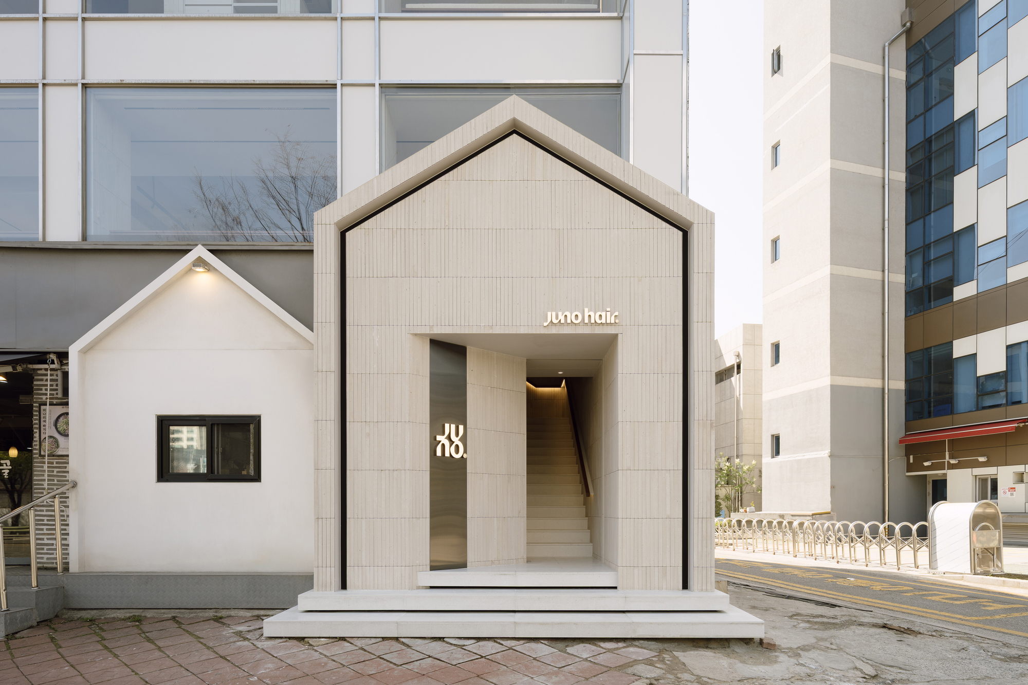 Exterior view of gabled timber pavilion inserted between existing buildings on cobblestone street
