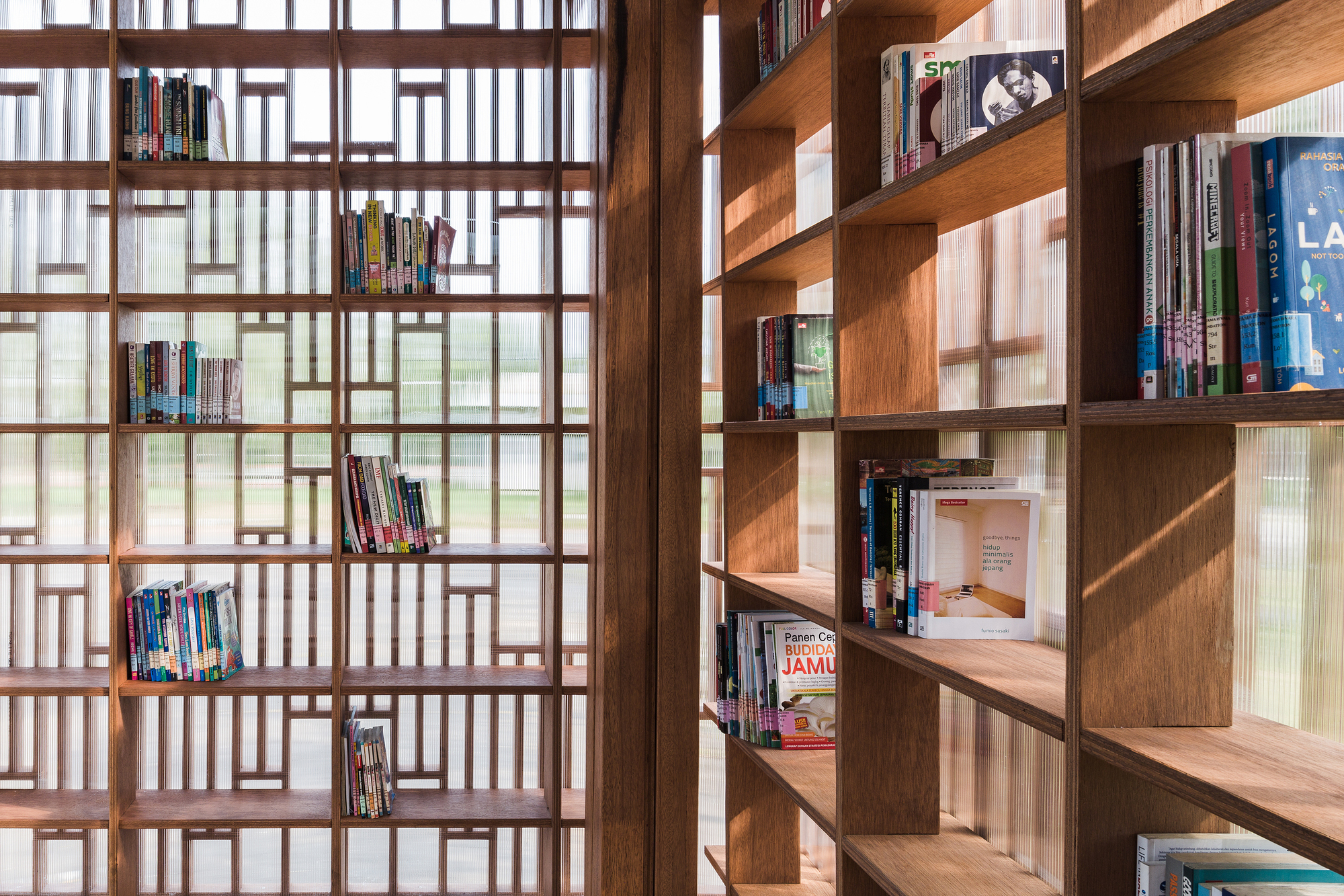 Interior bookshelves alongside patterned timber screen with diffused daylight filtering through translucent panels