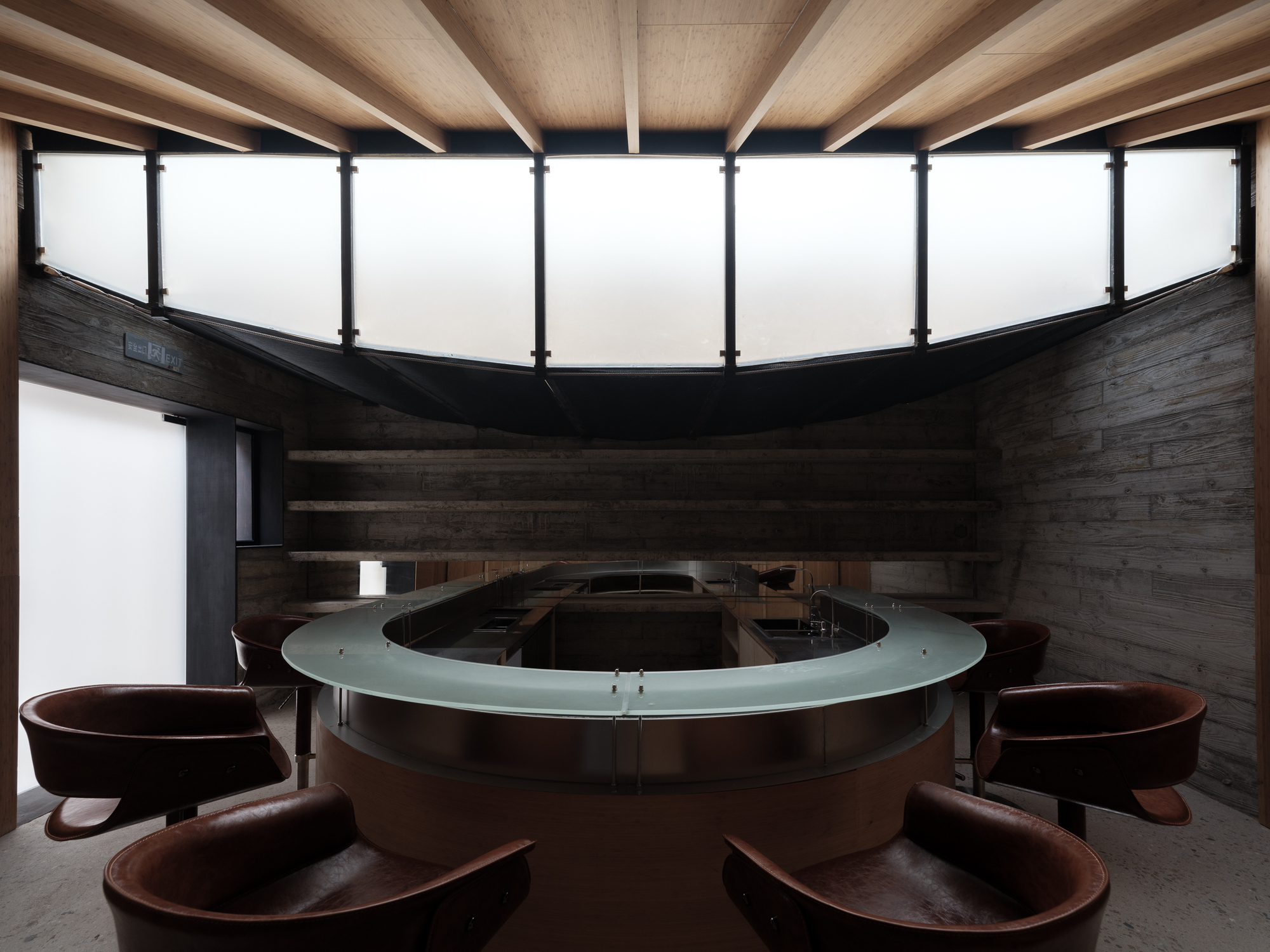 Circular clerestory window above a round communal bathing basin surrounded by timber tubs