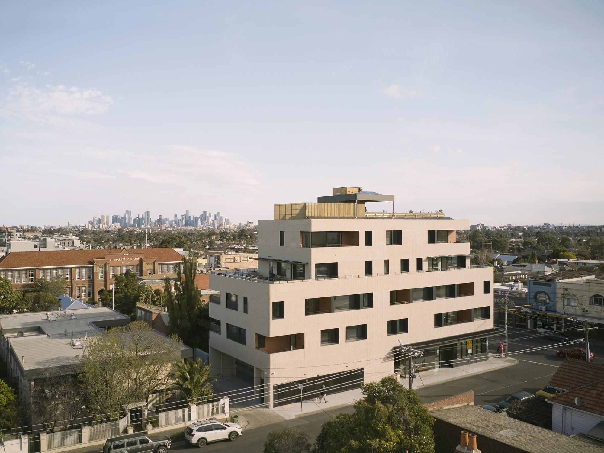 Elevated view of the offset floor plates and rooftop terrace with a distant skyline at dusk