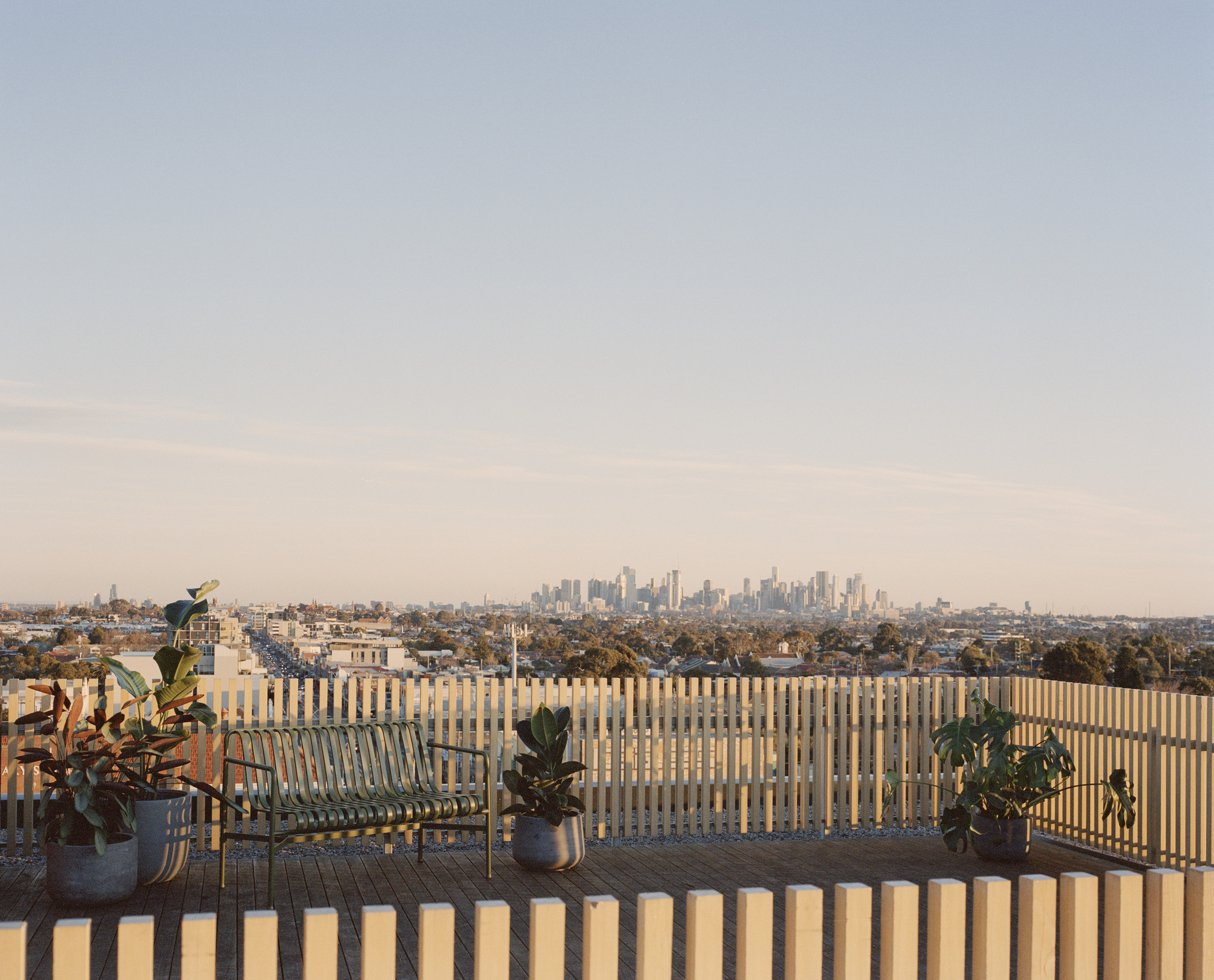 Rooftop terrace with vertical timber slat screen and potted plants overlooking the suburban horizon
