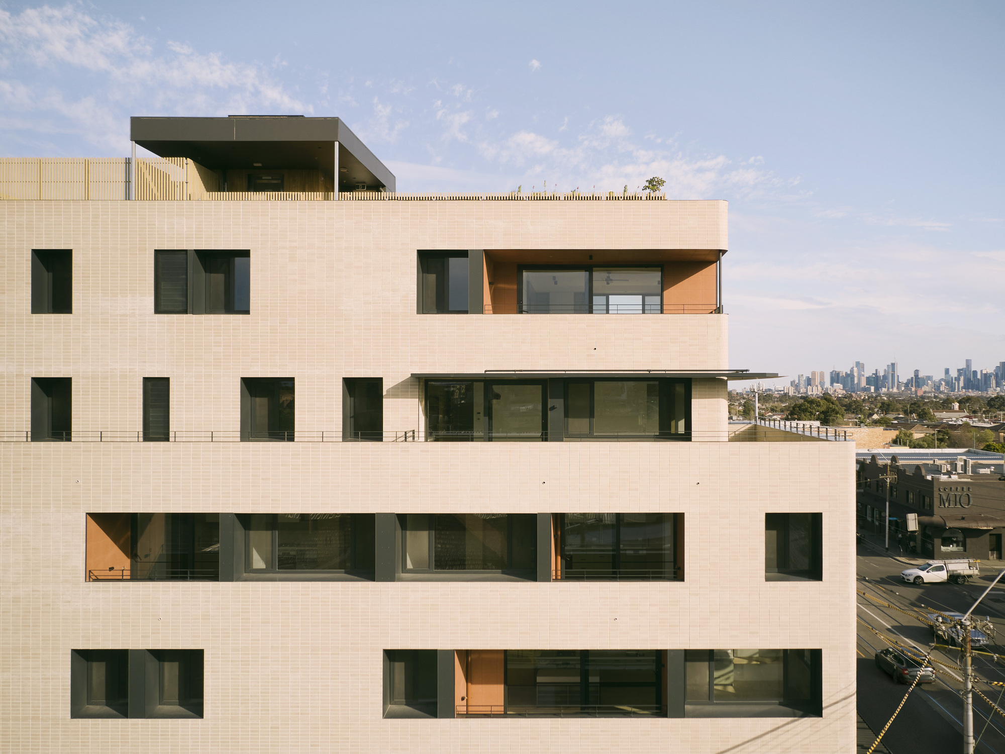 Facade detail showing the staggered balconies with timber soffits set into the textured tile skin