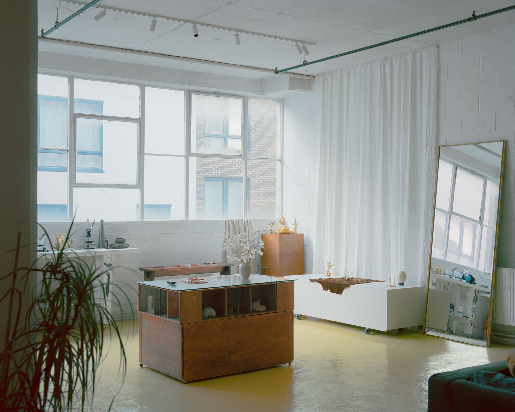 Open studio space with yellow resin flooring and large gridded windows framing brick buildings