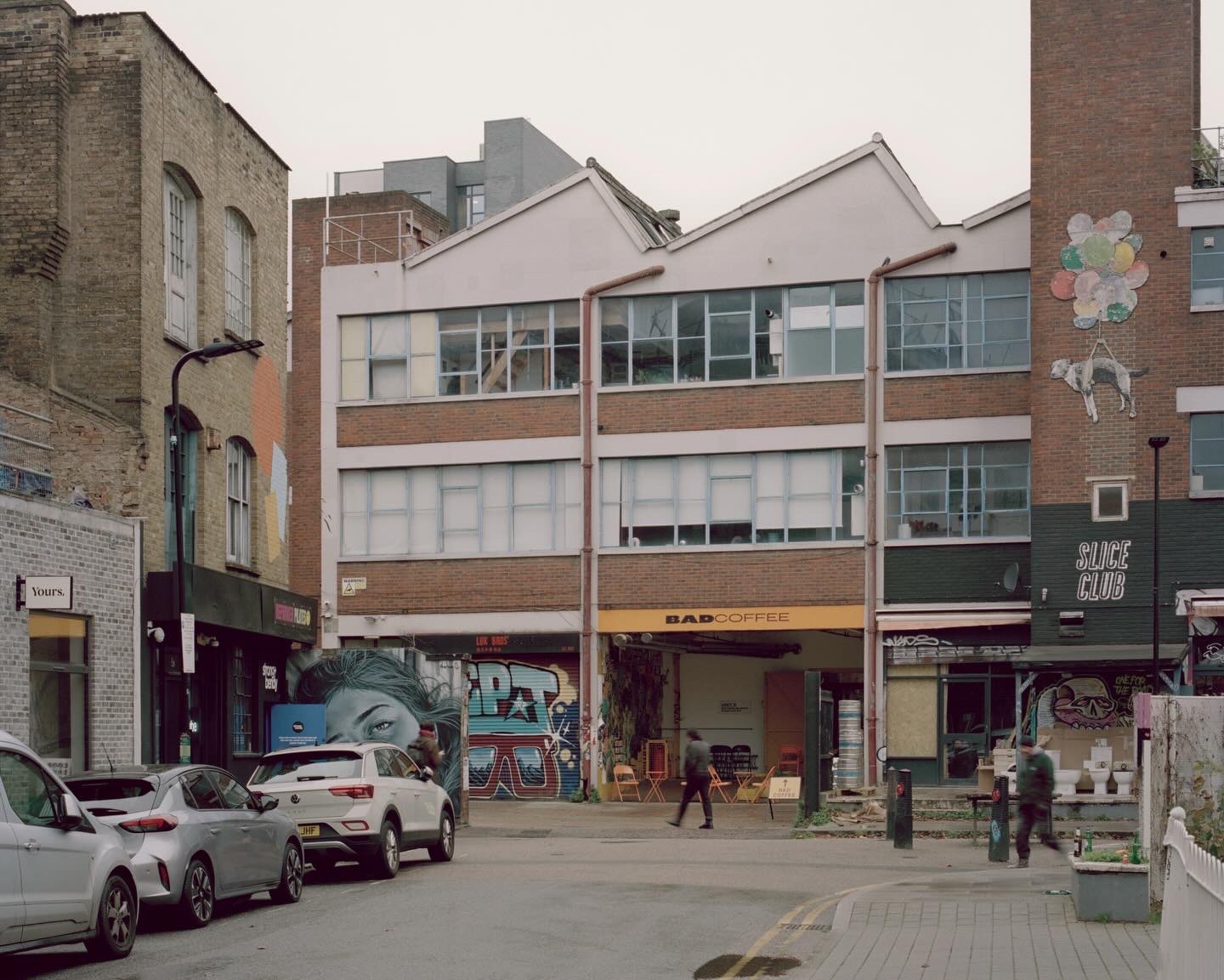 Street view of mixed-use building facades with exposed brick and storefronts with graffiti