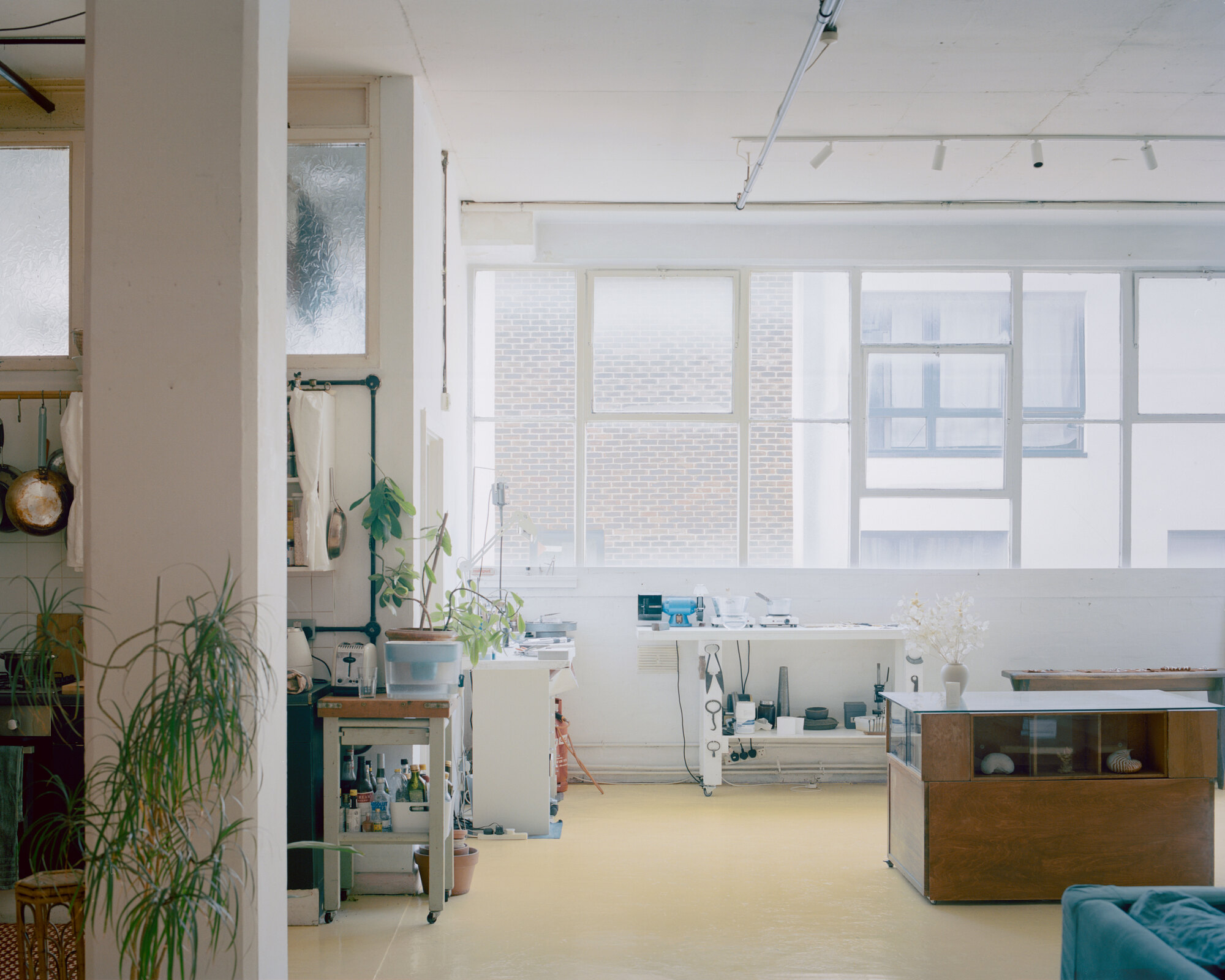 Studio space with yellow flooring, gridded windows, and freestanding furniture bathed in diffuse daylight