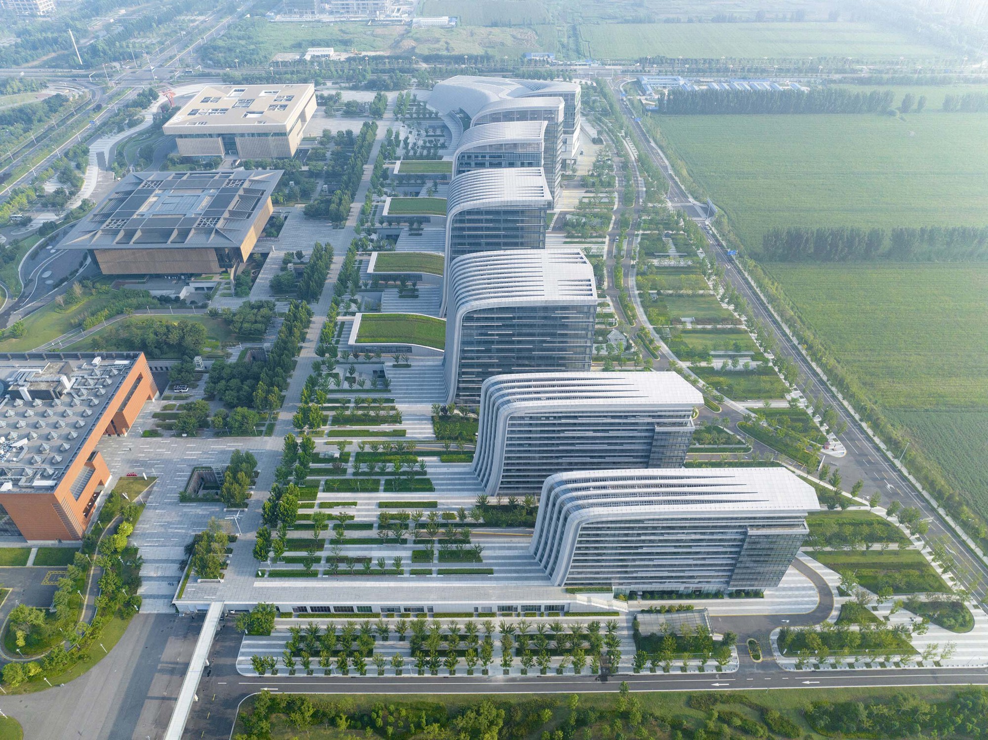 Aerial perspective showing the repeating ribbed facade rhythm of office towers along tree-lined streets