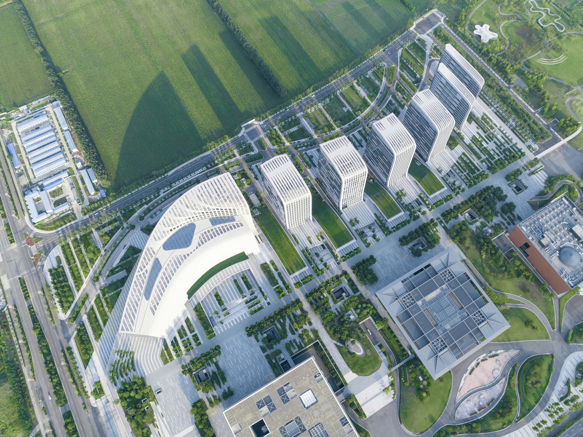 Overhead view of a crescent-shaped tower with horizontal banding beside rectangular blocks and courtyards