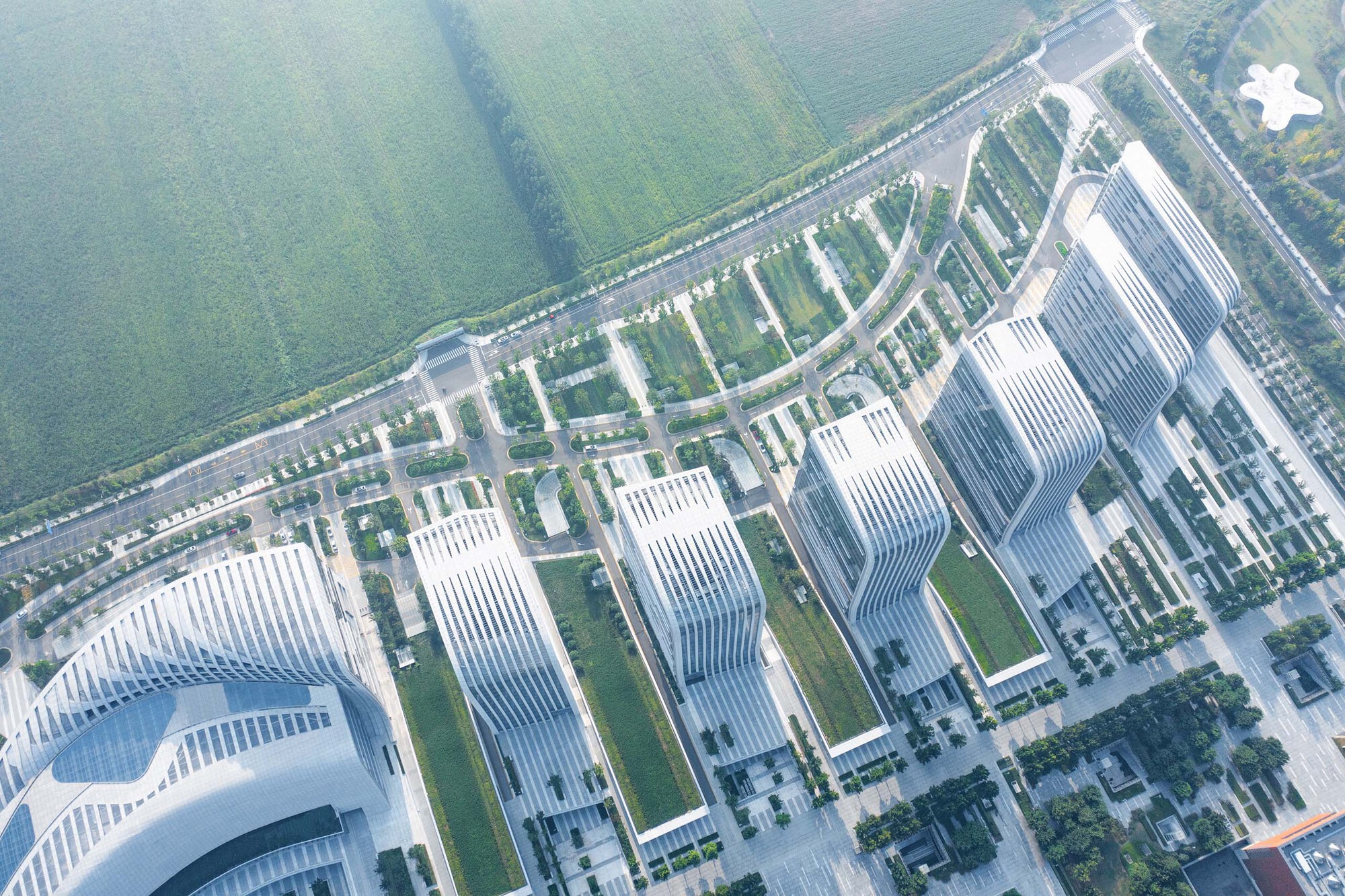 Oblique aerial of the undulating tower roofline and landscaped boulevards converging at a plaza