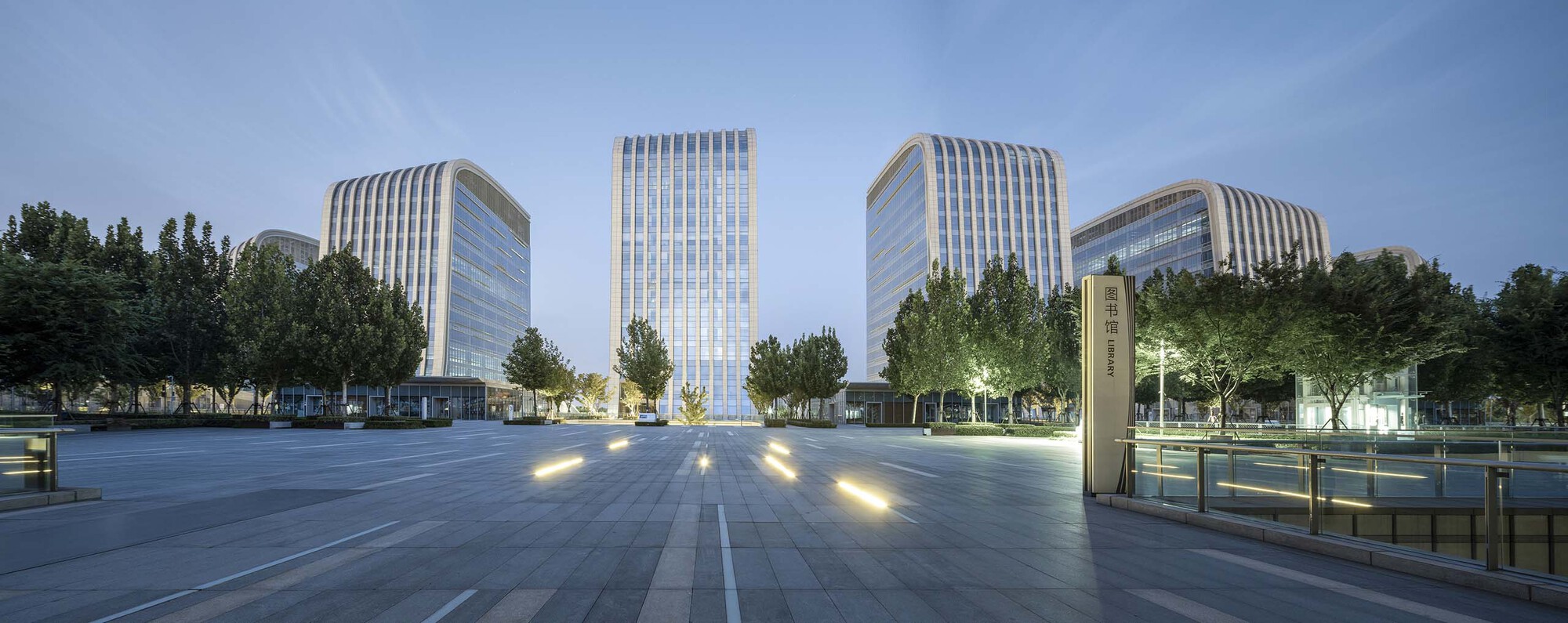 Wide plaza view with the tower cluster at dusk with ground lights illuminated