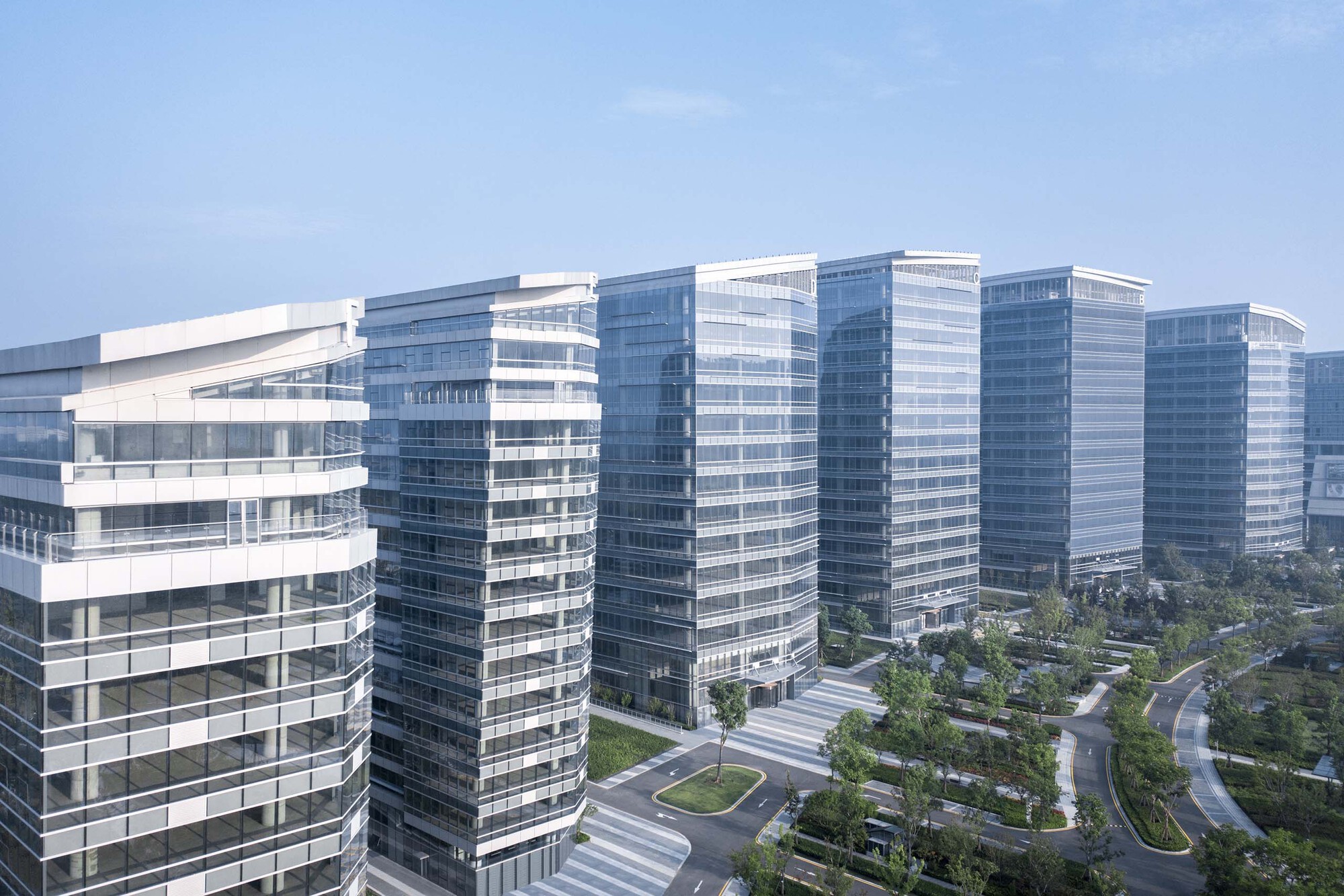 Horizontal banded glass facades of multiple towers above a landscaped courtyard with curved pathways