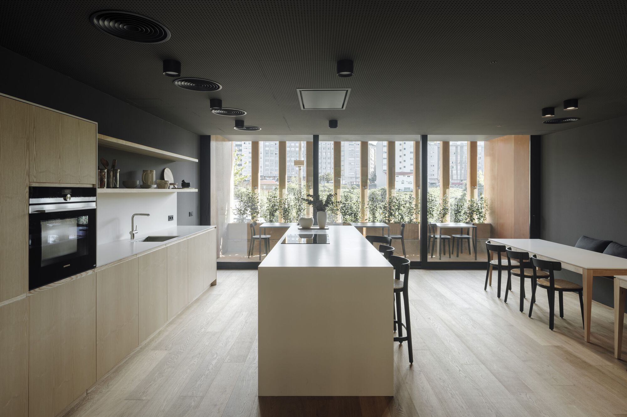 Kitchen and dining area with black corrugated ceiling and floor-to-ceiling windows to a terrace