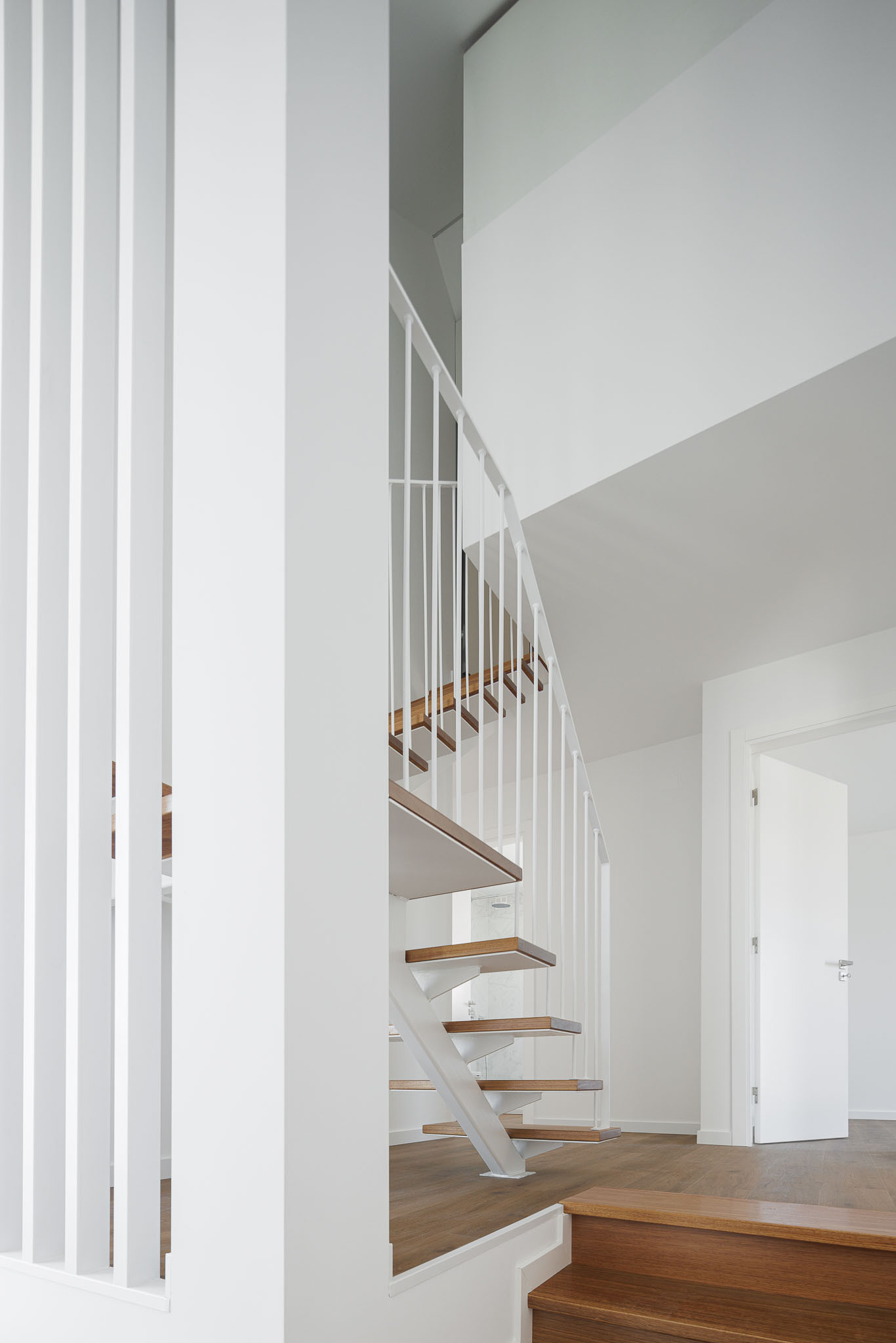 Upper landing view of steel and timber staircase with white vertical screen beside doorway