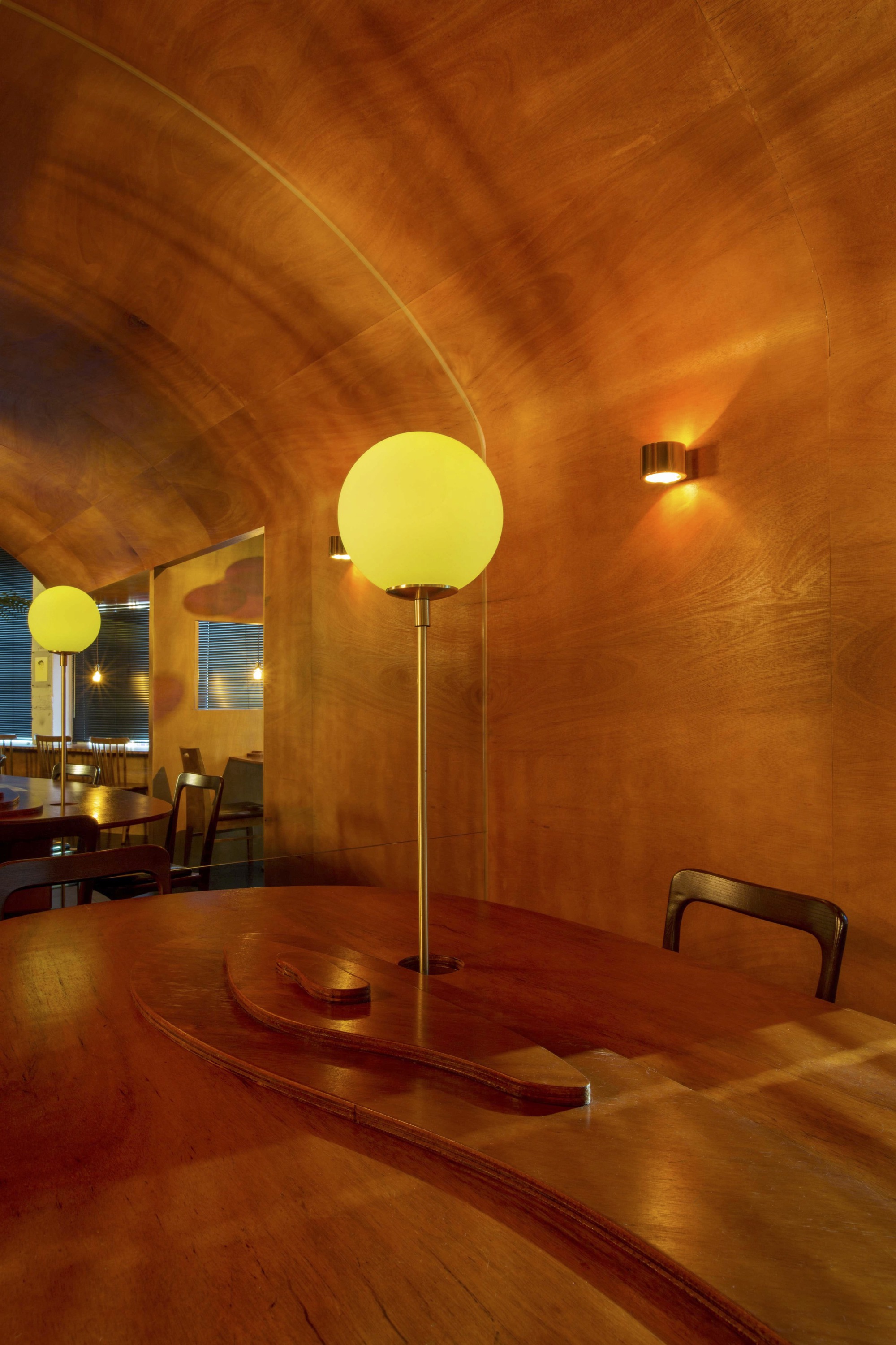 Detail of the laminated wood barrel vault curving above a spherical pendant and curved table edge