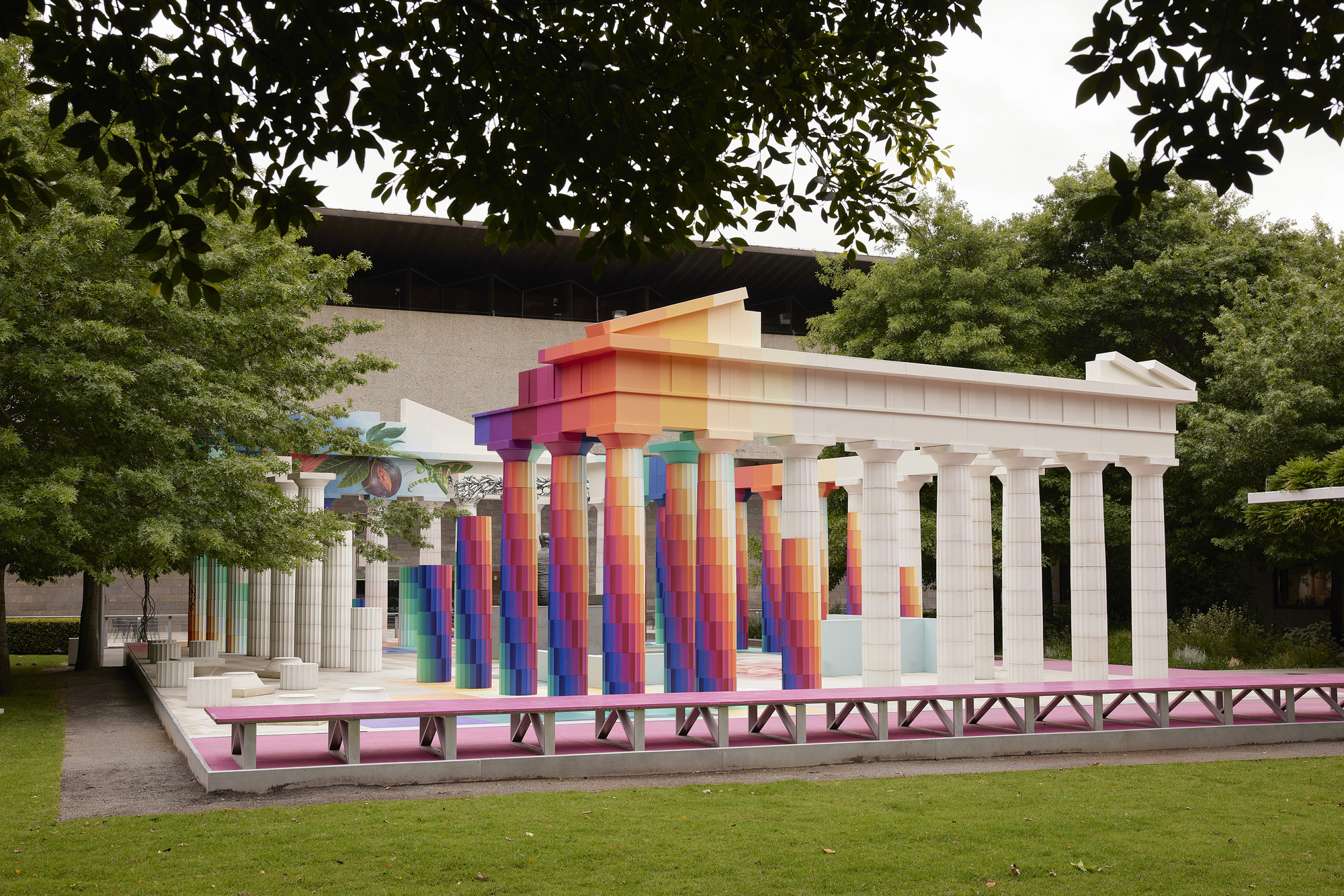 Side view of the pavilion with white fluted columns and gradient-painted entablature in a lawn setting