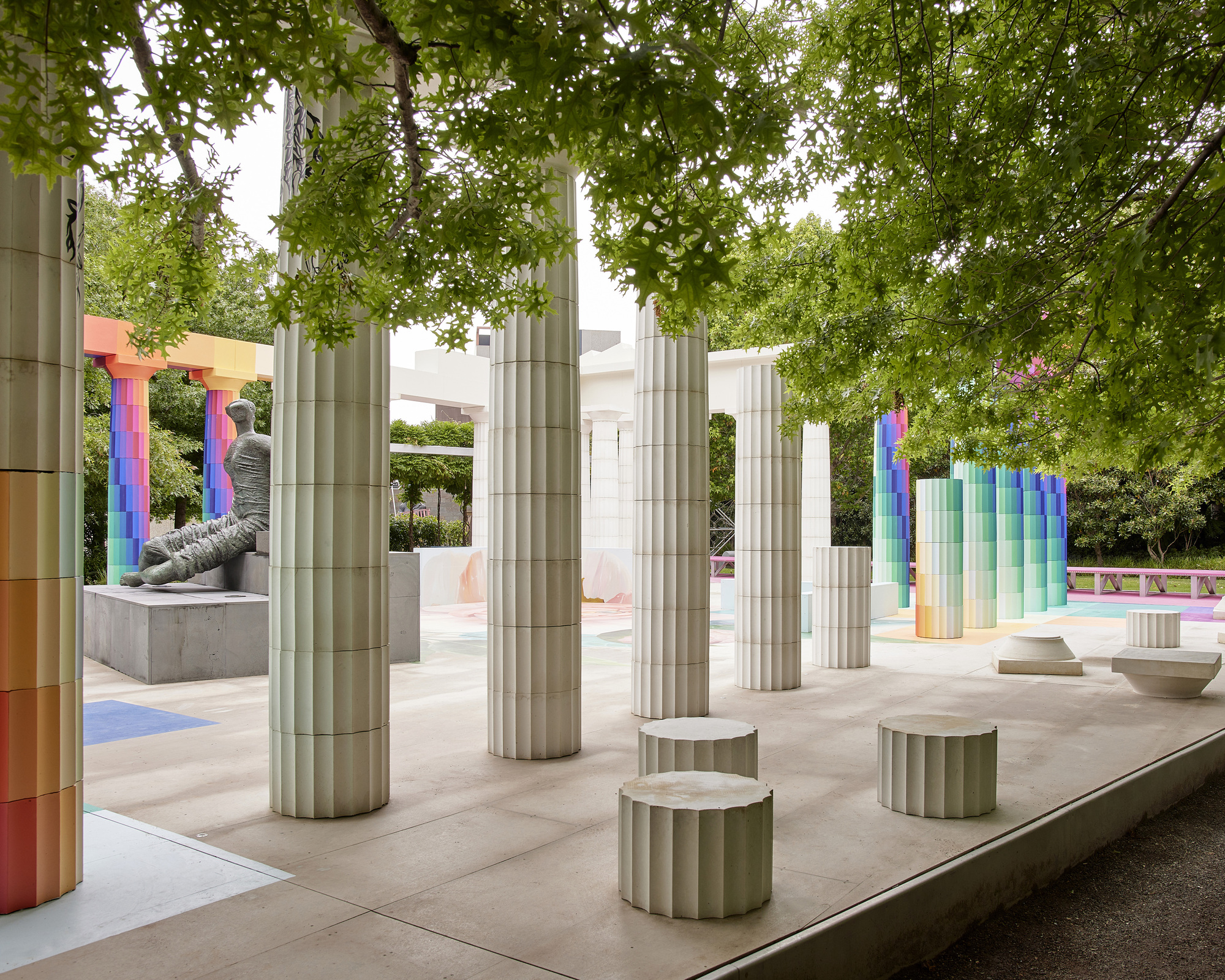 Interior view of the colonnade showing fluted cylindrical seats and gradient columns under leafy branches