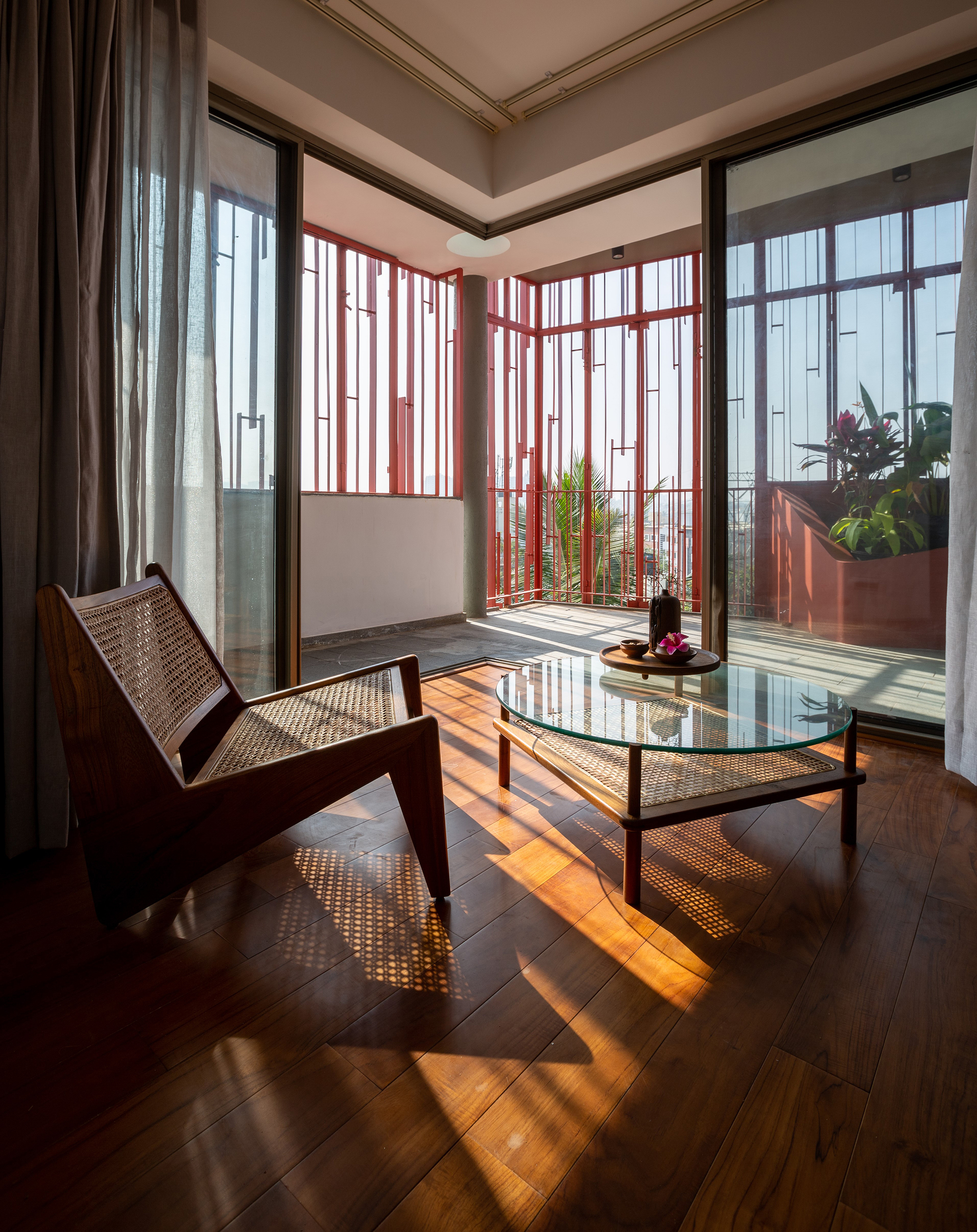 Interior living space with cane chairs and striped sunlight patterns from the red batten enclosure