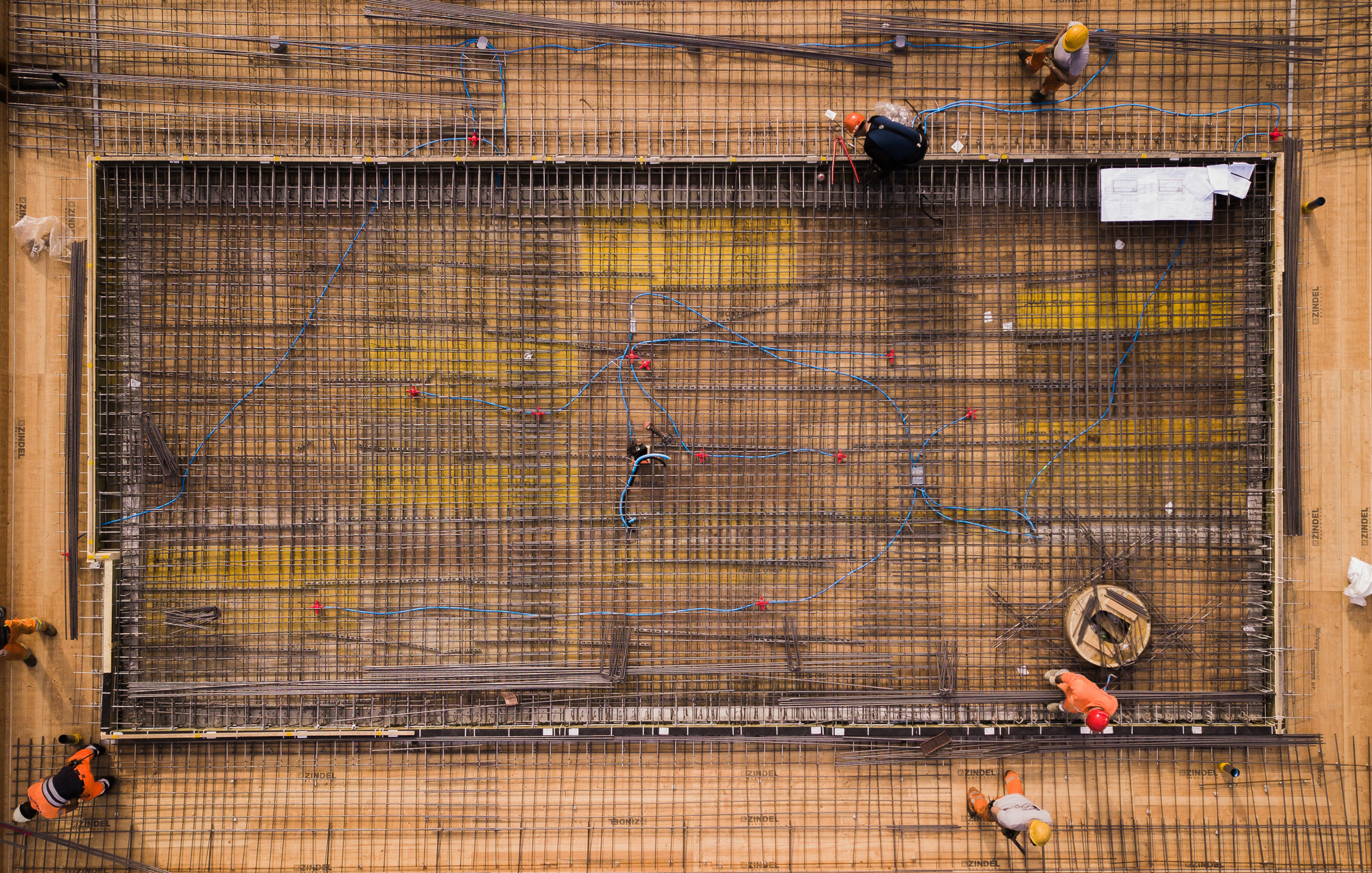 Overhead view of reinforcement mesh grid laid across timber formwork with workers during concrete preparation