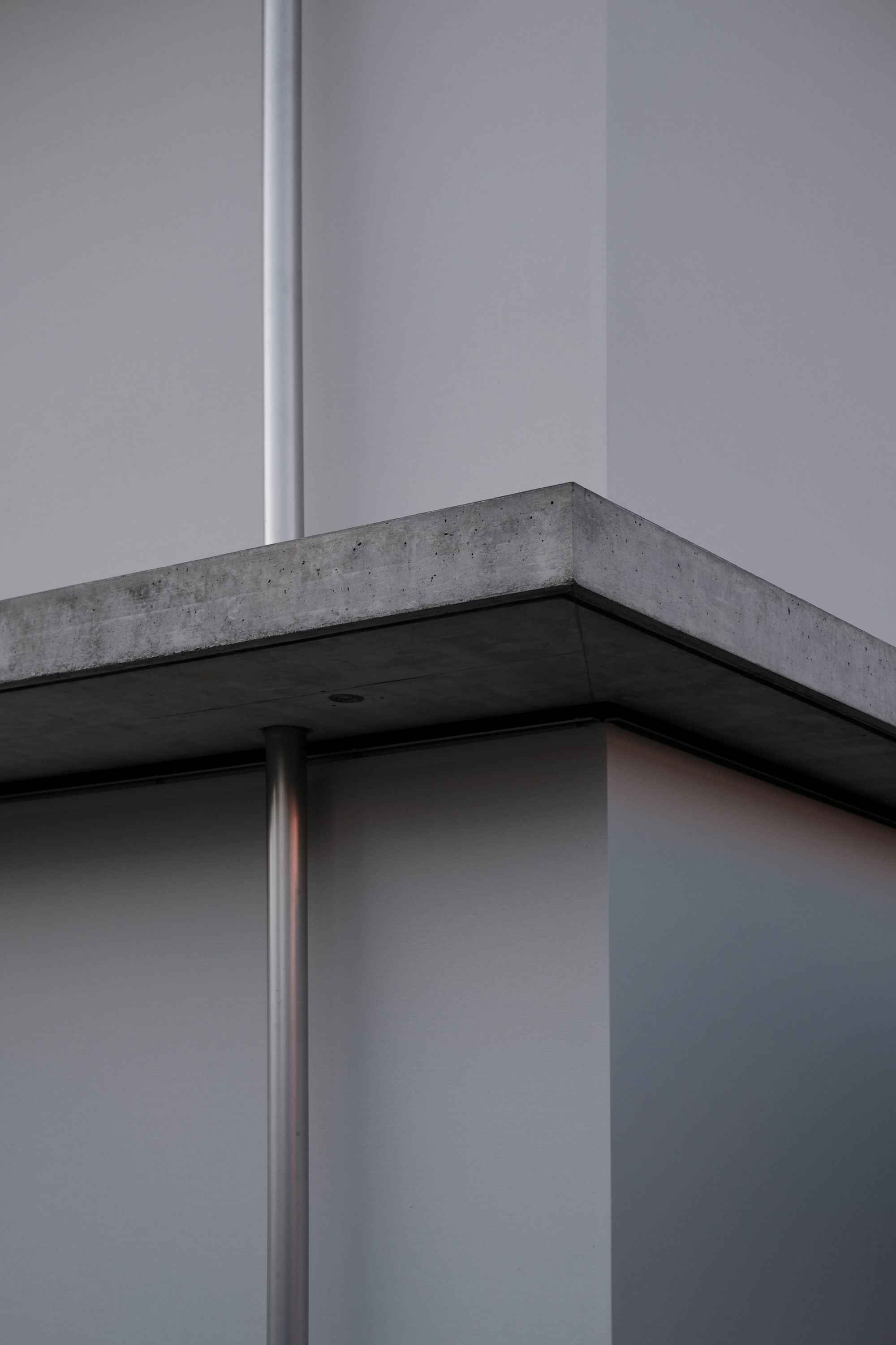 Close-up of concrete beam corner supported by steel column with recessed black soffit panel