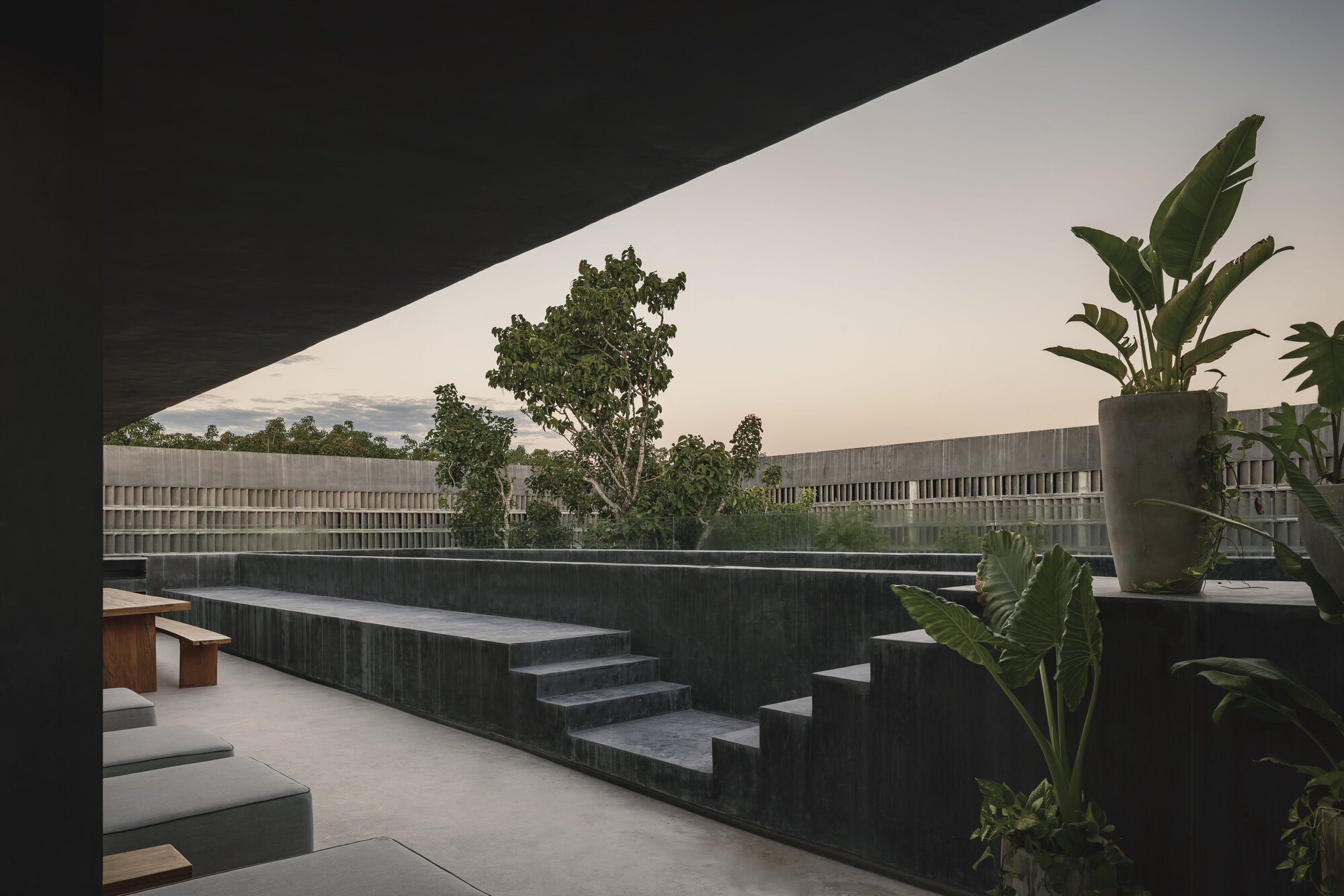 Rooftop terrace with dark concrete stepped seating and planters under an overcast sky