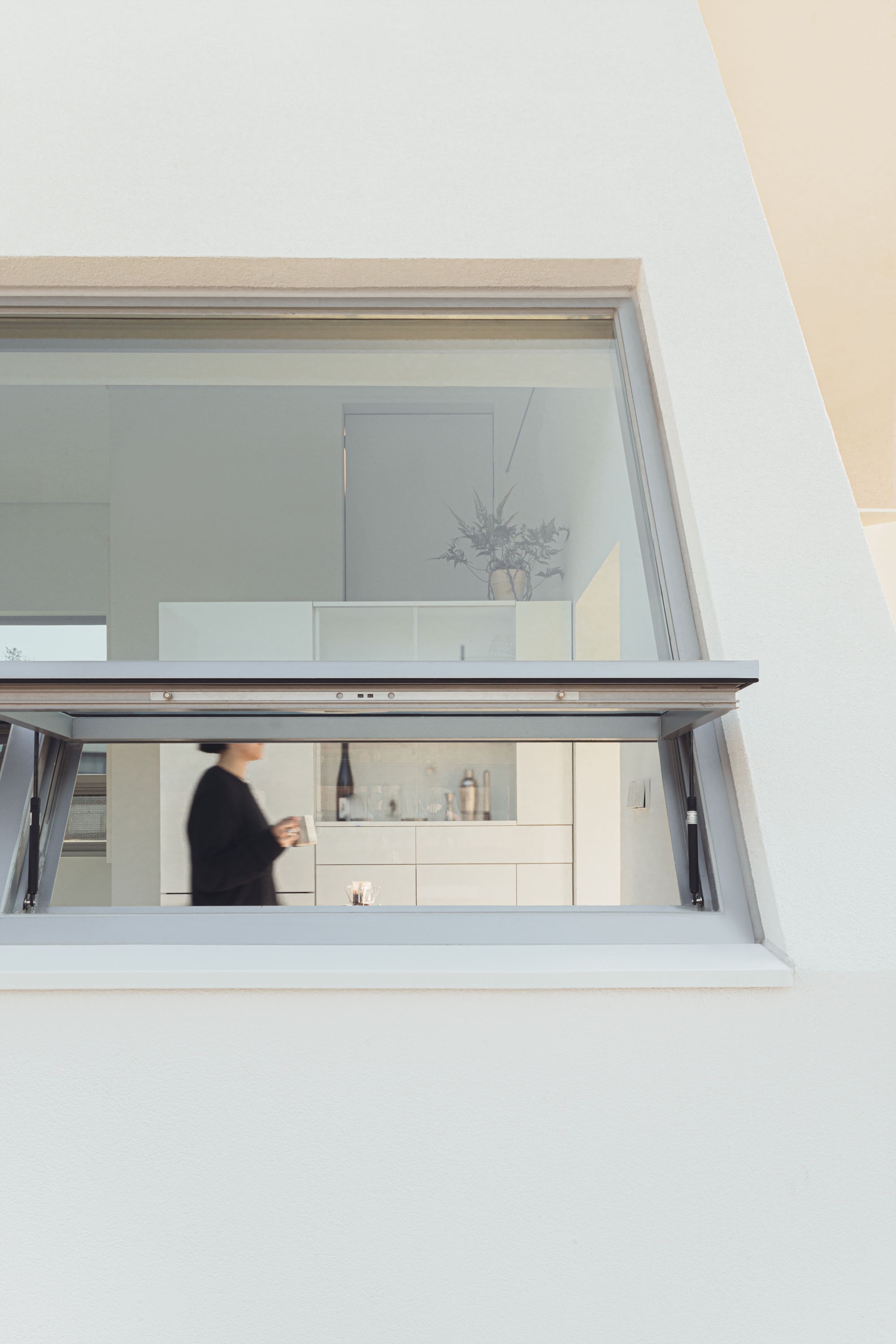 Kitchen pass-through window with glass folding doors and a figure moving inside
