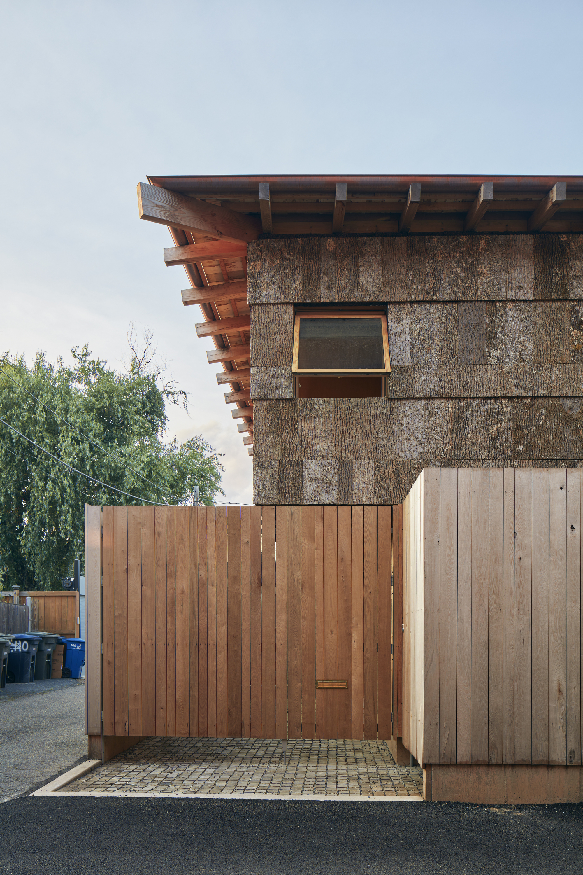 Corner detail of the cantilevered rafters above straw panel wall and timber gate enclosure