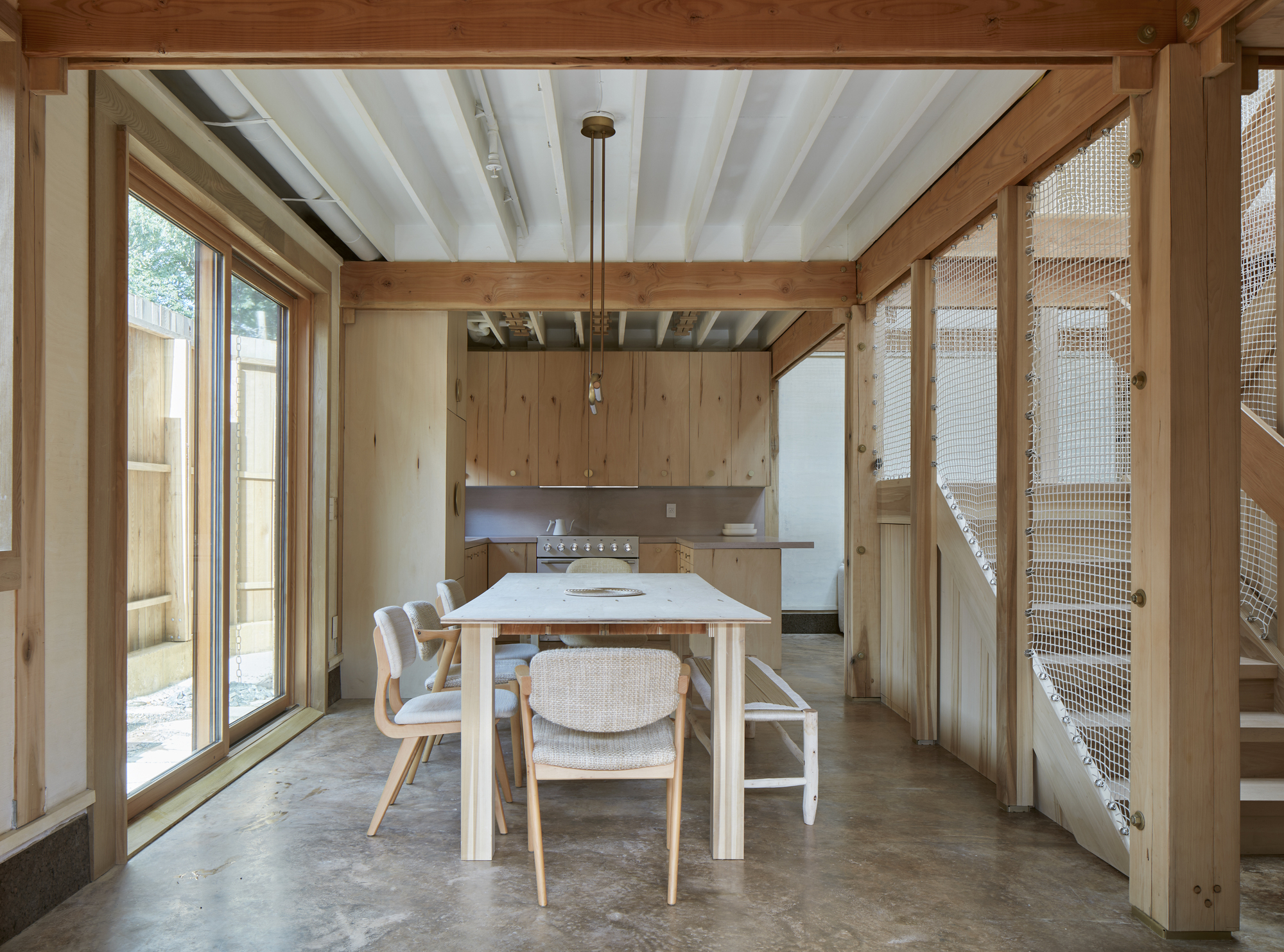 Dining area with exposed timber frame, painted ceiling beams and mesh-panel stair enclosure