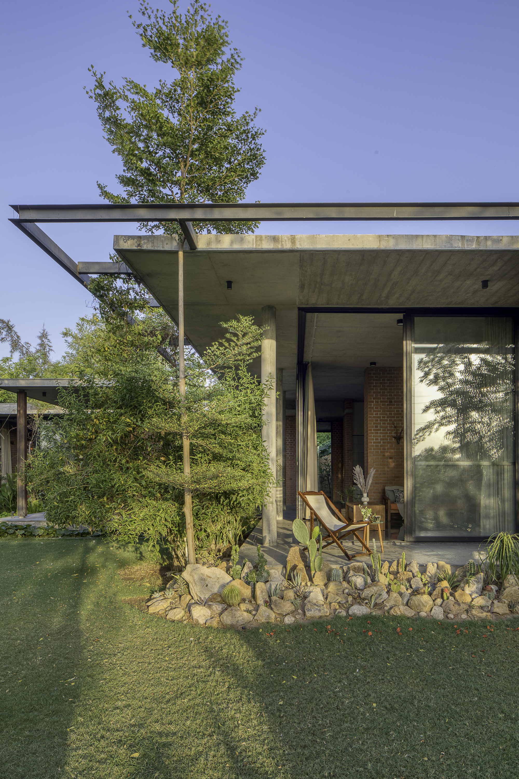 Cantilevered concrete roof overhang above the glazed entrance with cacti and rock garden in foreground
