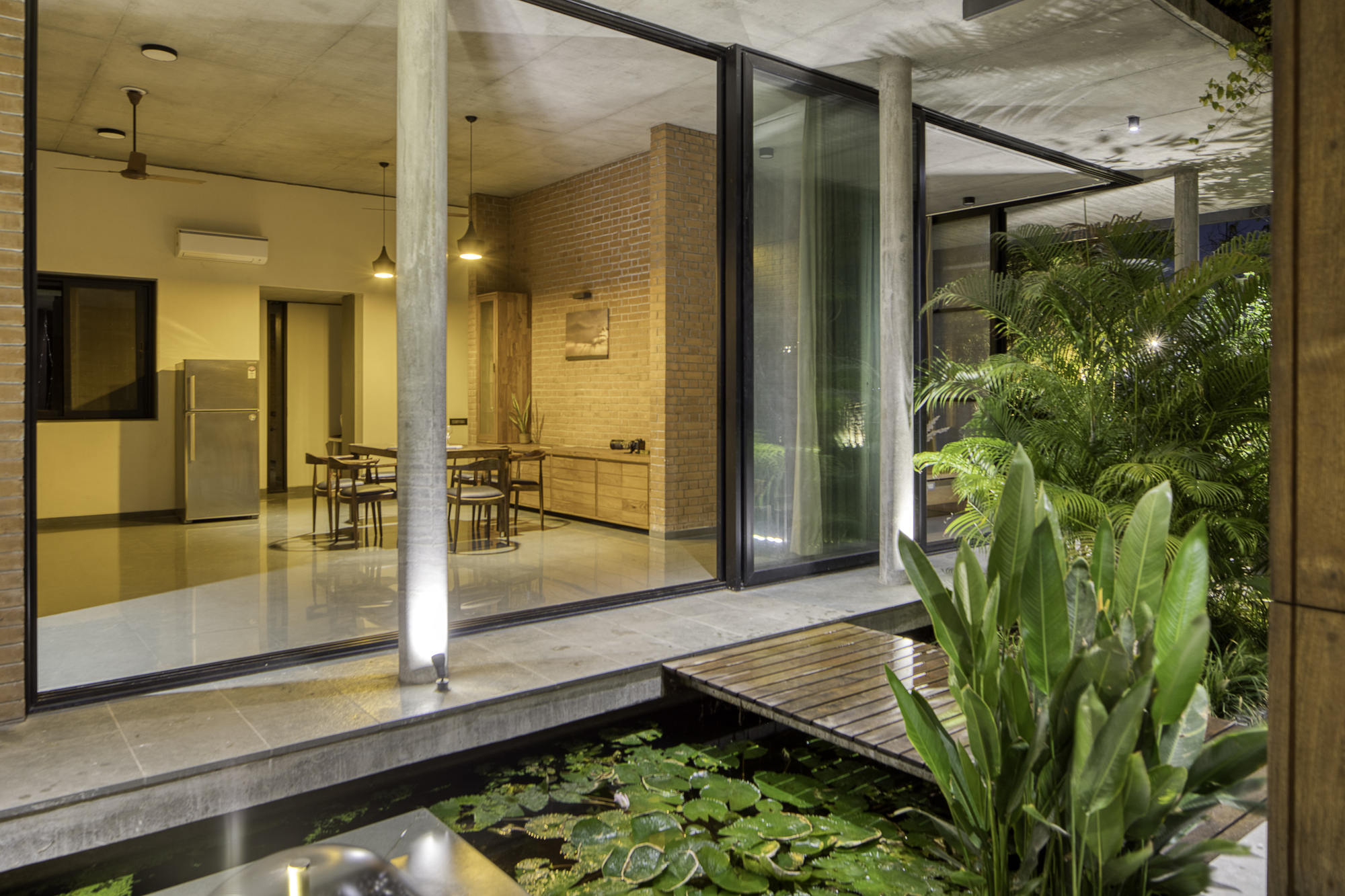 Interior courtyard with lily pond and sliding glass doors opening to dining area under concrete ceiling