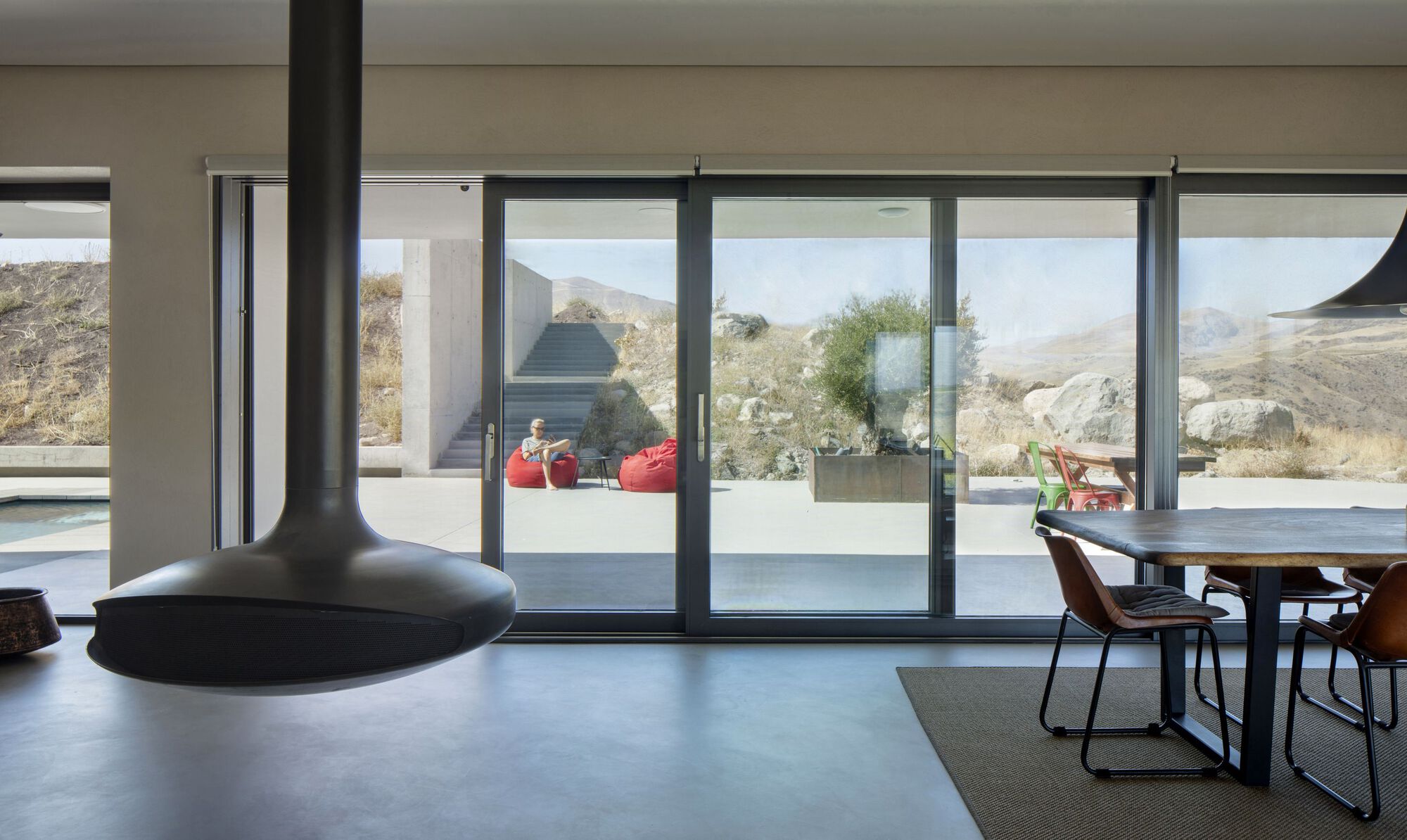 Interior living space with pendant fireplace and sliding glass doors opening to a terrace with mountain views