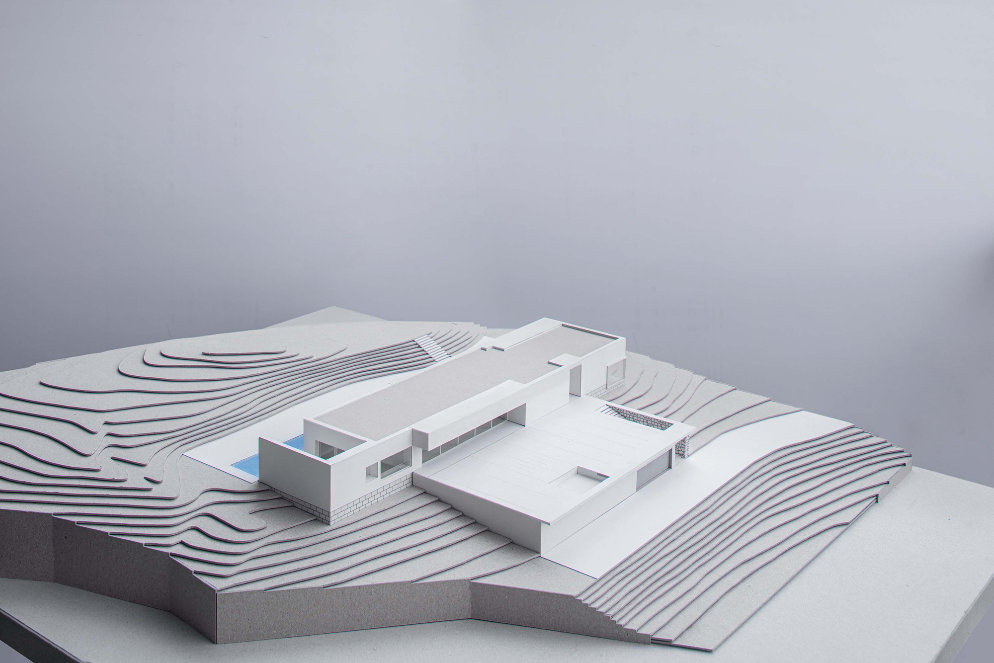 Physical model showing terraced site contours surrounding a flat-roofed residence with pool courtyard