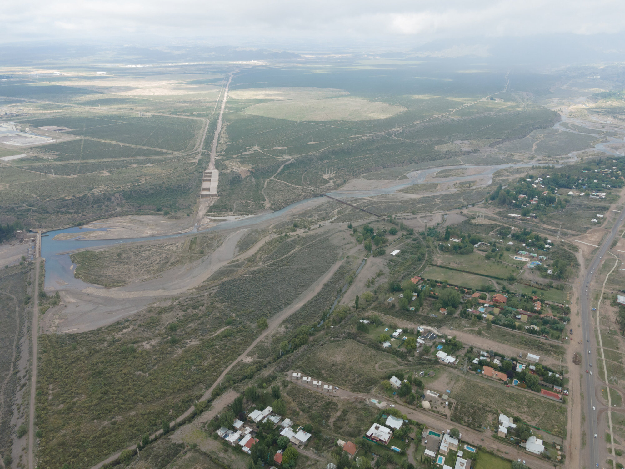 Wide aerial view showing the housing cluster within a patchwork landscape of roads and waterways
